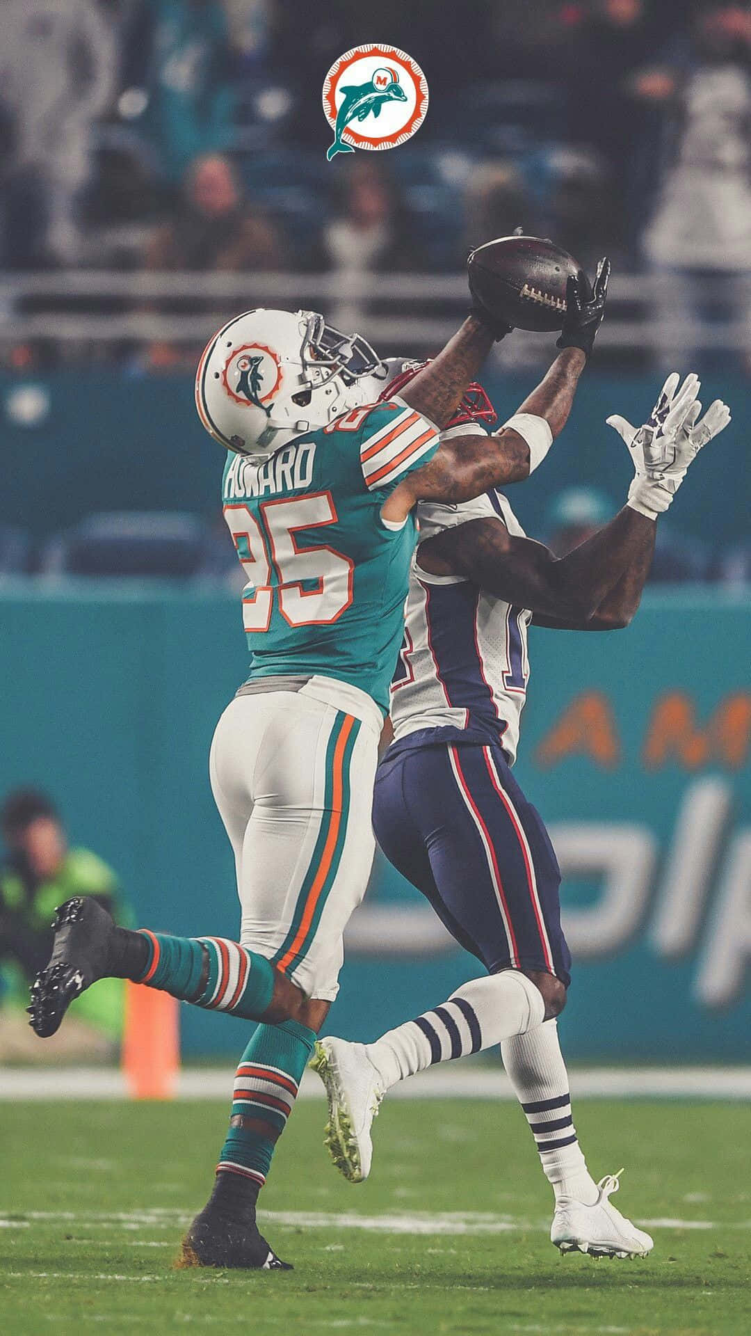 Xavien Howard接球瞬間 壁紙 — 兩名足球運動員在球場燈光下躍起進行戲劇性的接球，背景是模糊的球迷。