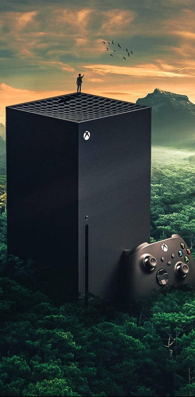 Xbox Series X 在森林中 壁紙 — 一部巨大的Xbox主機從森林中升起，旁邊有一個控制器，一個孤獨的身影站在其屋頂上，背景是夕陽天空。