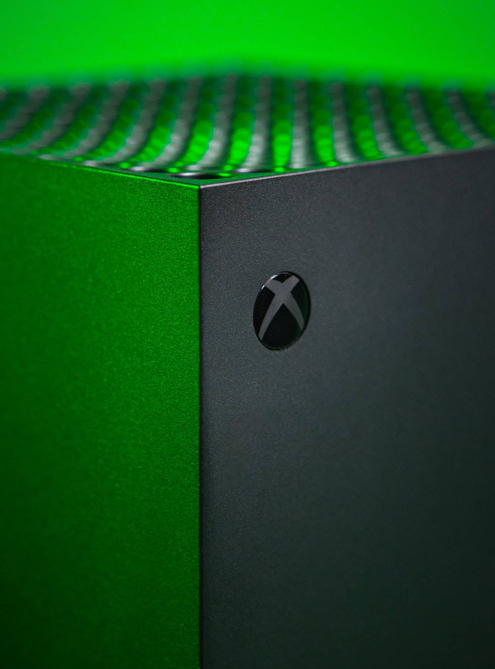 Xbox Series X 灰色磨砂主機 壁紙 — Xbox 主機特寫，帶有充滿活力的綠色發光通風口和霧面黑色外殼。