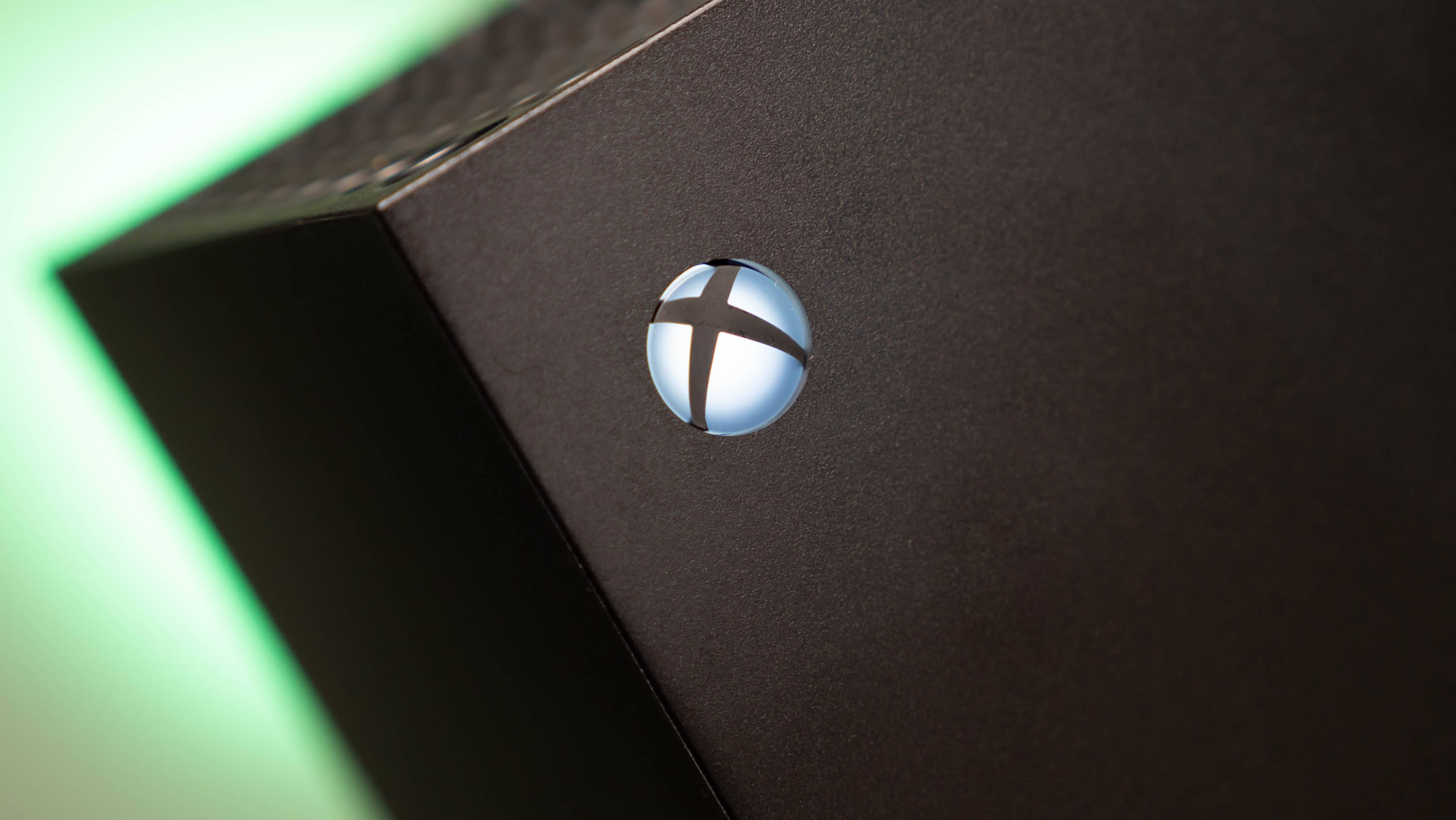 Xbox Series X 藍色標誌 壁紙 — 黑色Xbox主機特寫，帶有發光的綠色環境光和發亮的標誌。
