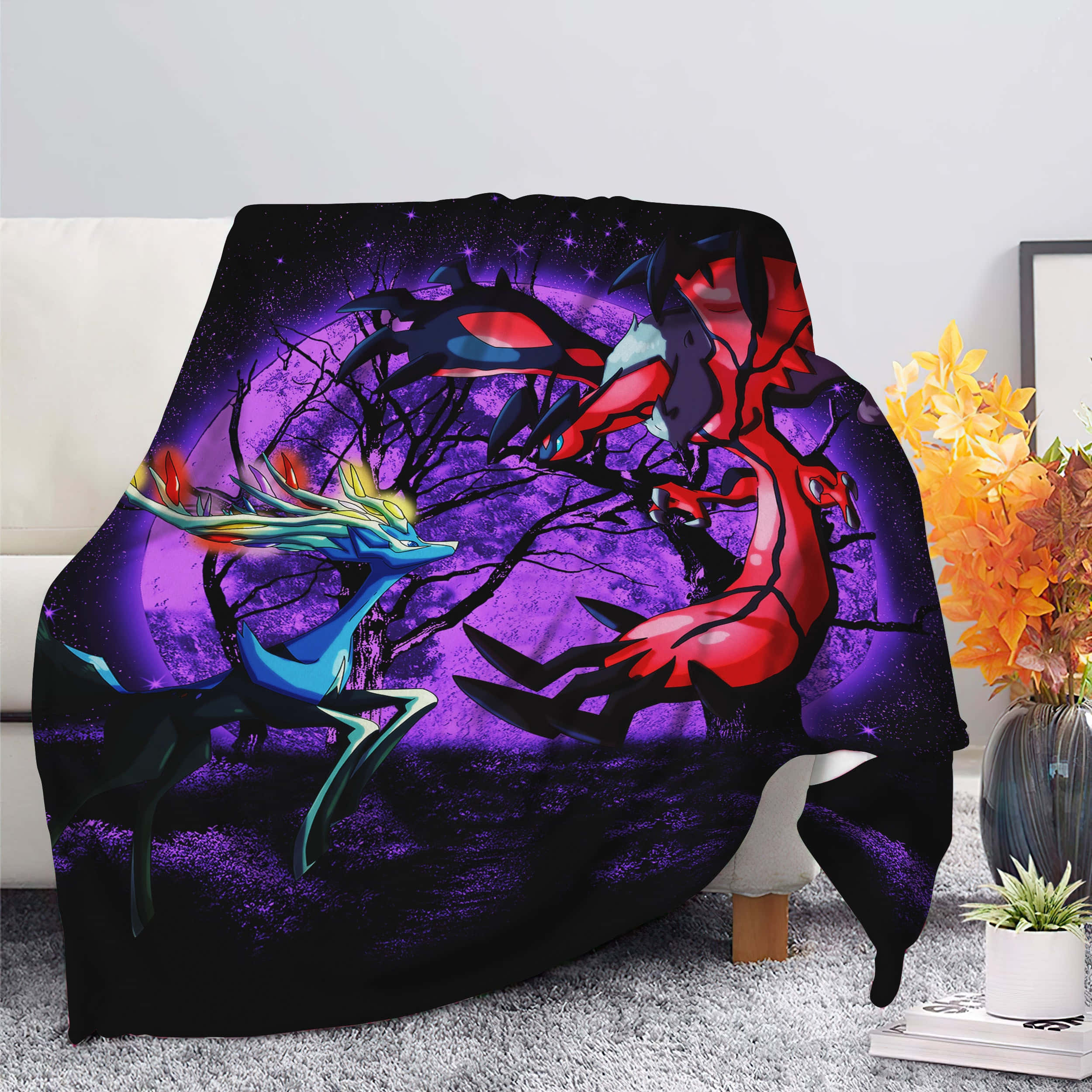 Xerneas 與 Yveltal 印於布料上 壁紙 — 一張充滿活力的動漫風格毯子披在椅子上，展示了一隻發光的藍色鹿和一隻紅龍在紫色星空背景下對峙。