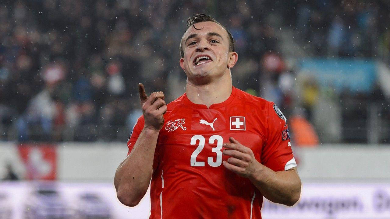 Xherdan Shaqiri 勝利足球賽場 壁紙 — 一位身穿紅色23號球衣的瑞士足球員在傾盆大雨中熱情慶祝，背景是體育場的人群。