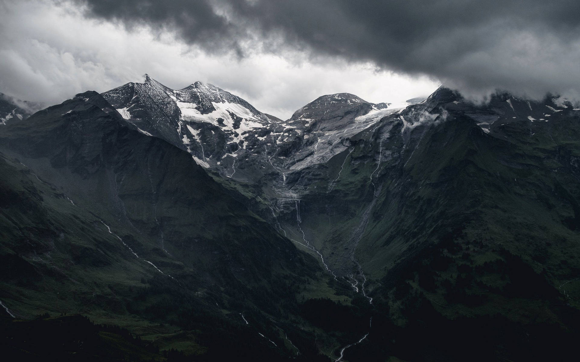 暴風雨的山脈，白雪覆蓋的山峰和頭頂的烏雲。
