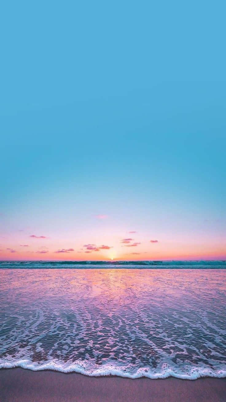  壁紙 — 夕陽將天空和海洋染成柔和的粉紅色和藍色，溫柔的海浪拍打著海岸。