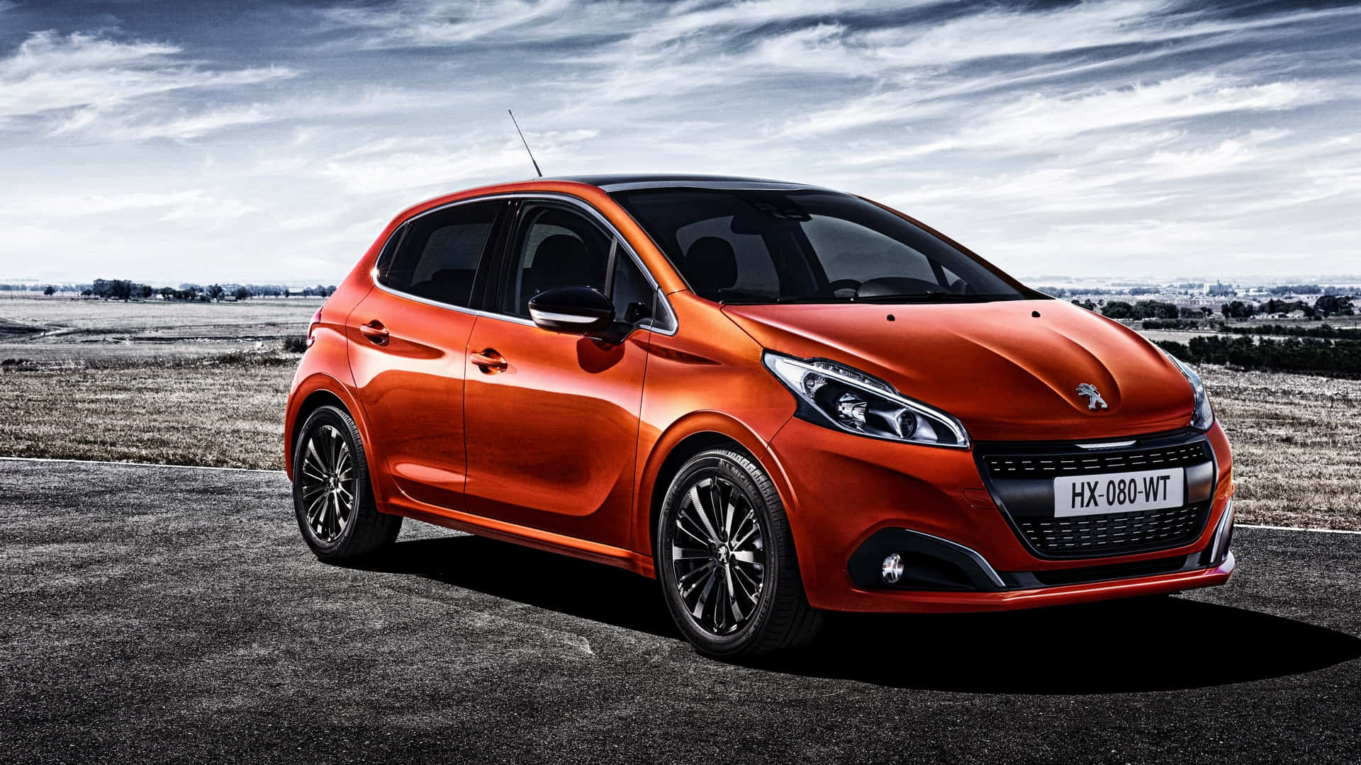 Peugeot 208 桌布 壁紙 — 一輛鮮橙色的標緻208跑車停泊在瀝青路上，天空多雲，背景是平坦的風景。