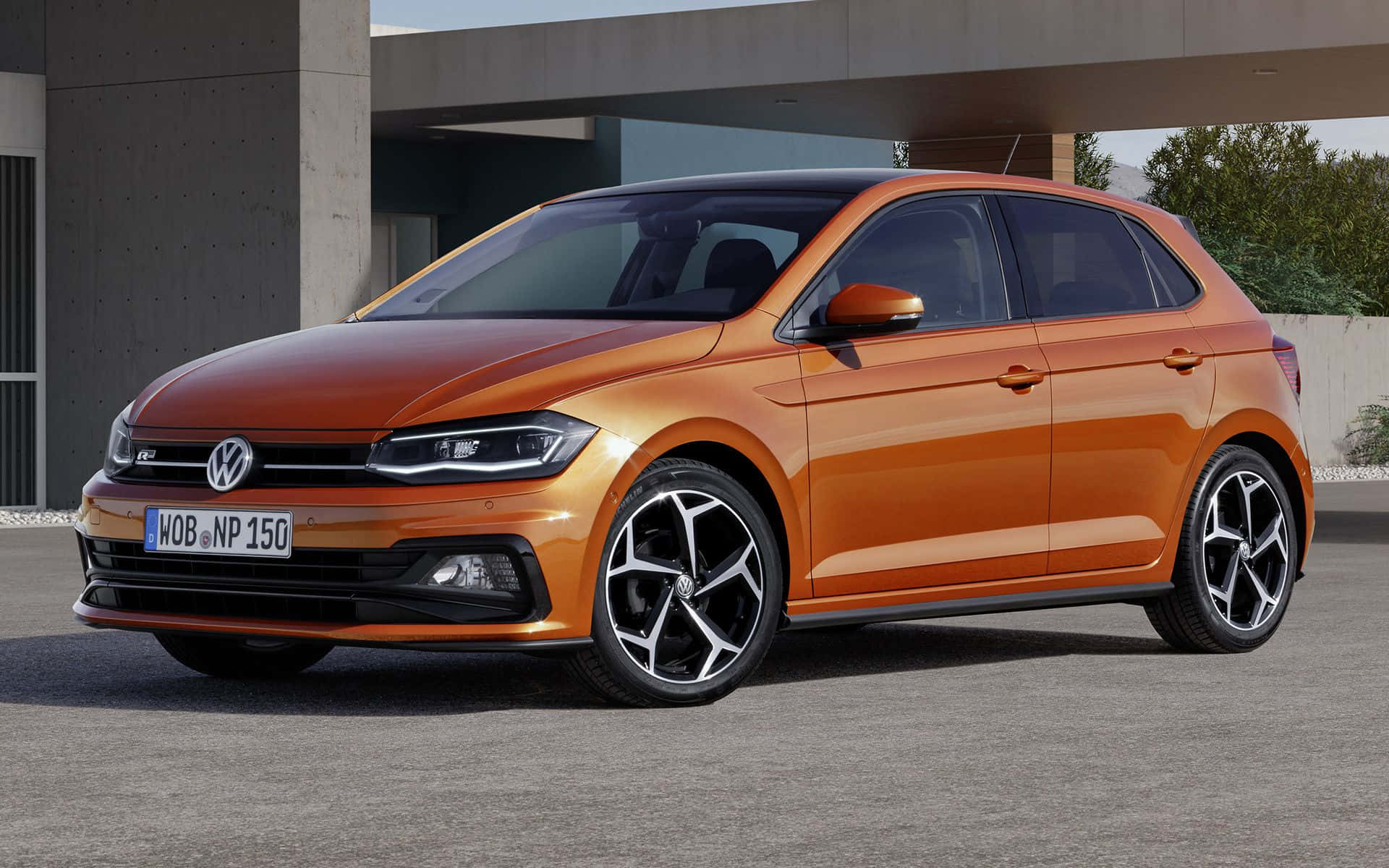 Volkswagen Polo 桌布 壁紙 — 一輛鮮橙色的福士Polo掀背車，配備時尚黑色合金輪圈，停泊在現代混凝土結構下。