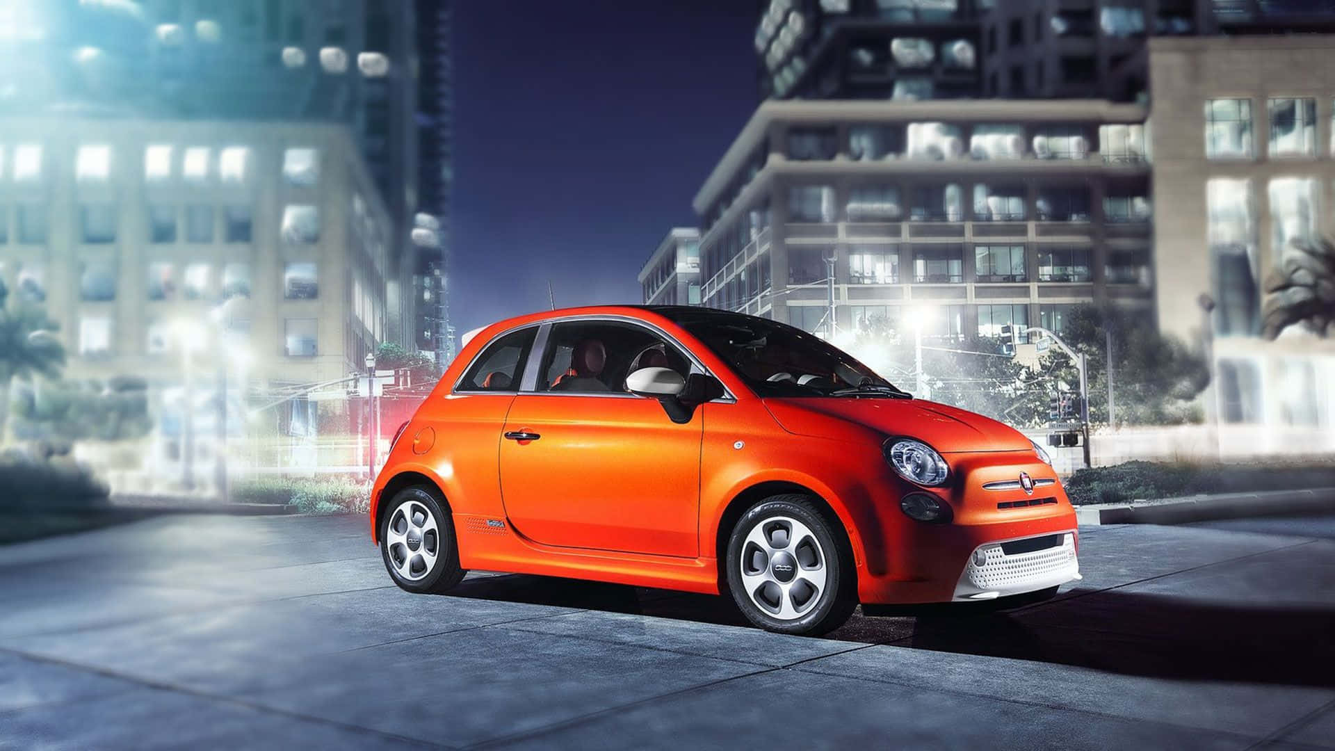 Fiat 500l 桌布 壁紙 — 一輛鮮橙色的菲亞特500在夜間停泊在濕漉漉的城市街道上，背景有發光的建築物燈光。