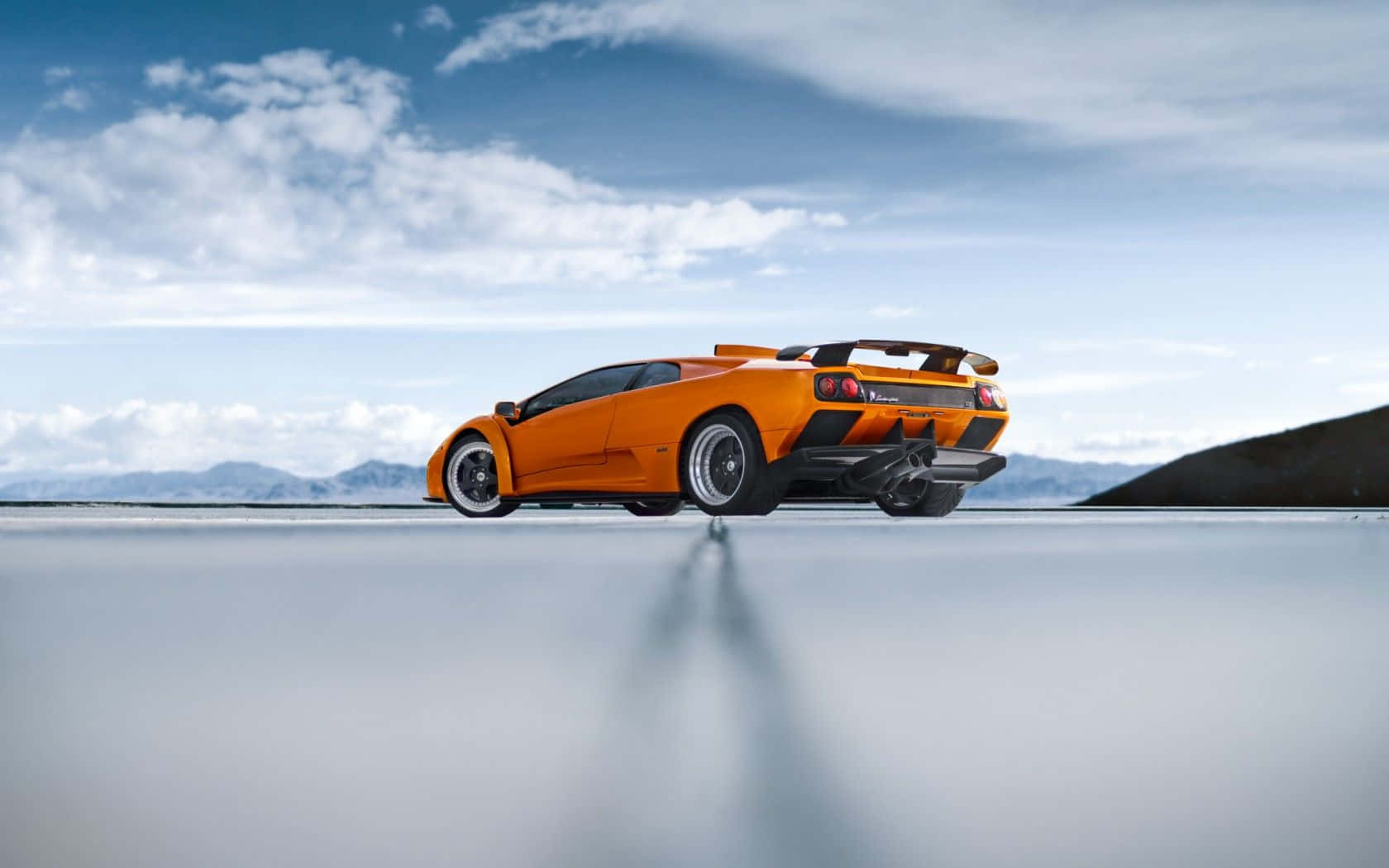 Lamborghini Diablo 桌布 壁紙 — 一輛鮮橙色的林寶堅尼 Murciélago 停在反射的鹽灘上，背景是廣闊的藍天和散落的雲朵。
