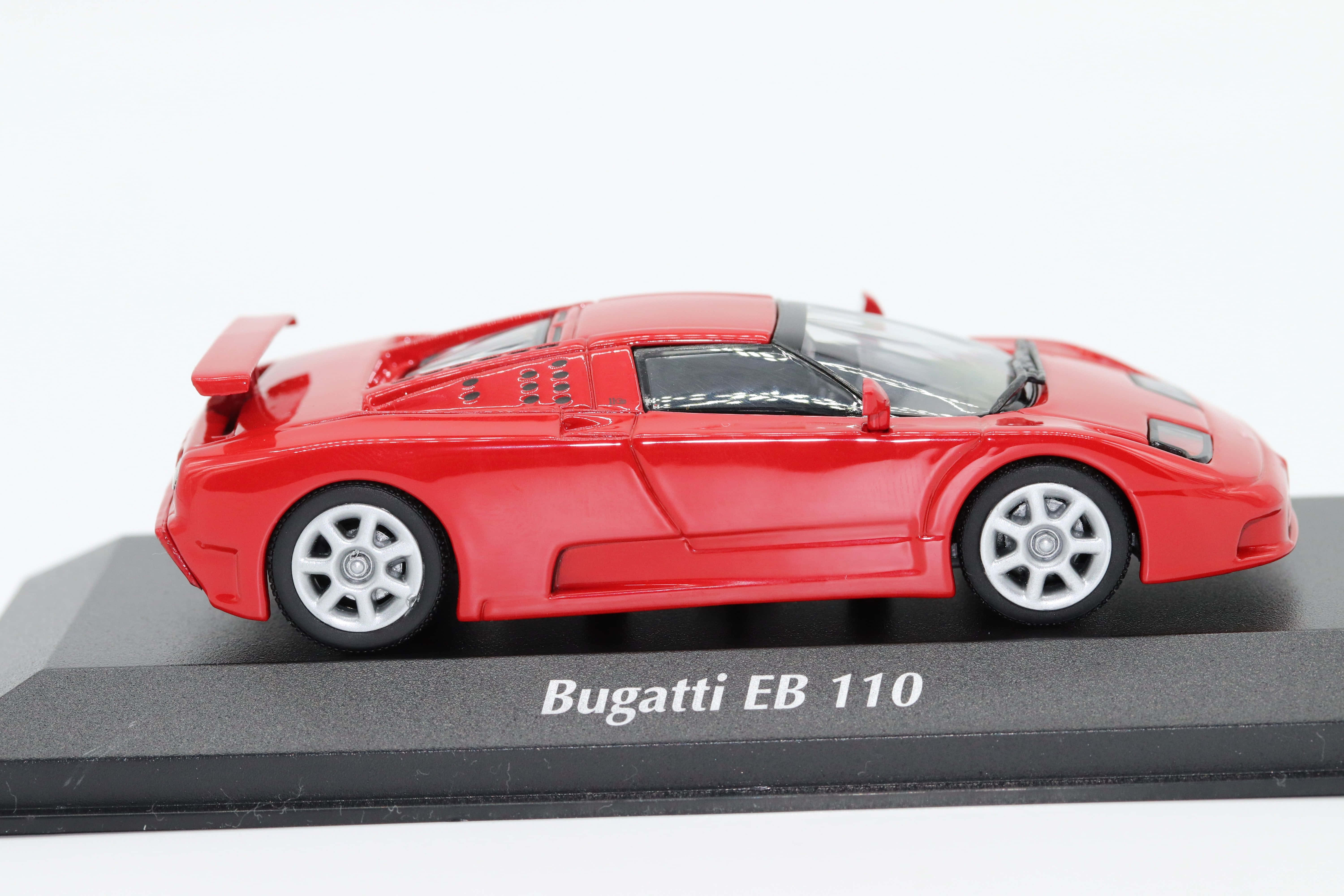 Bugatti Eb110 桌布 壁紙 — 一輛鮮紅色的Bugatti EB 110壓鑄模型車，展示在黑色底座上，帶有白色文字，背景為純白色。
