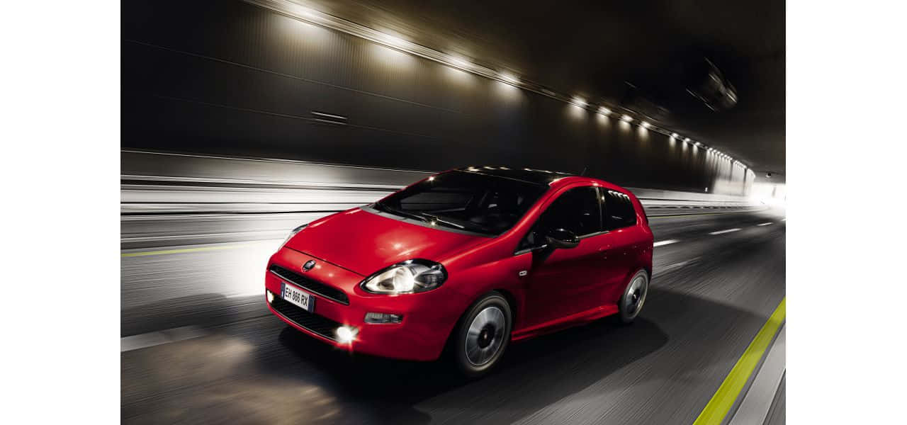 Fiat Punto 桌布 壁紙 — 一輛鮮紅色的Fiat Punto在昏暗的隧道中疾馳，帶有動態模糊的痕跡。