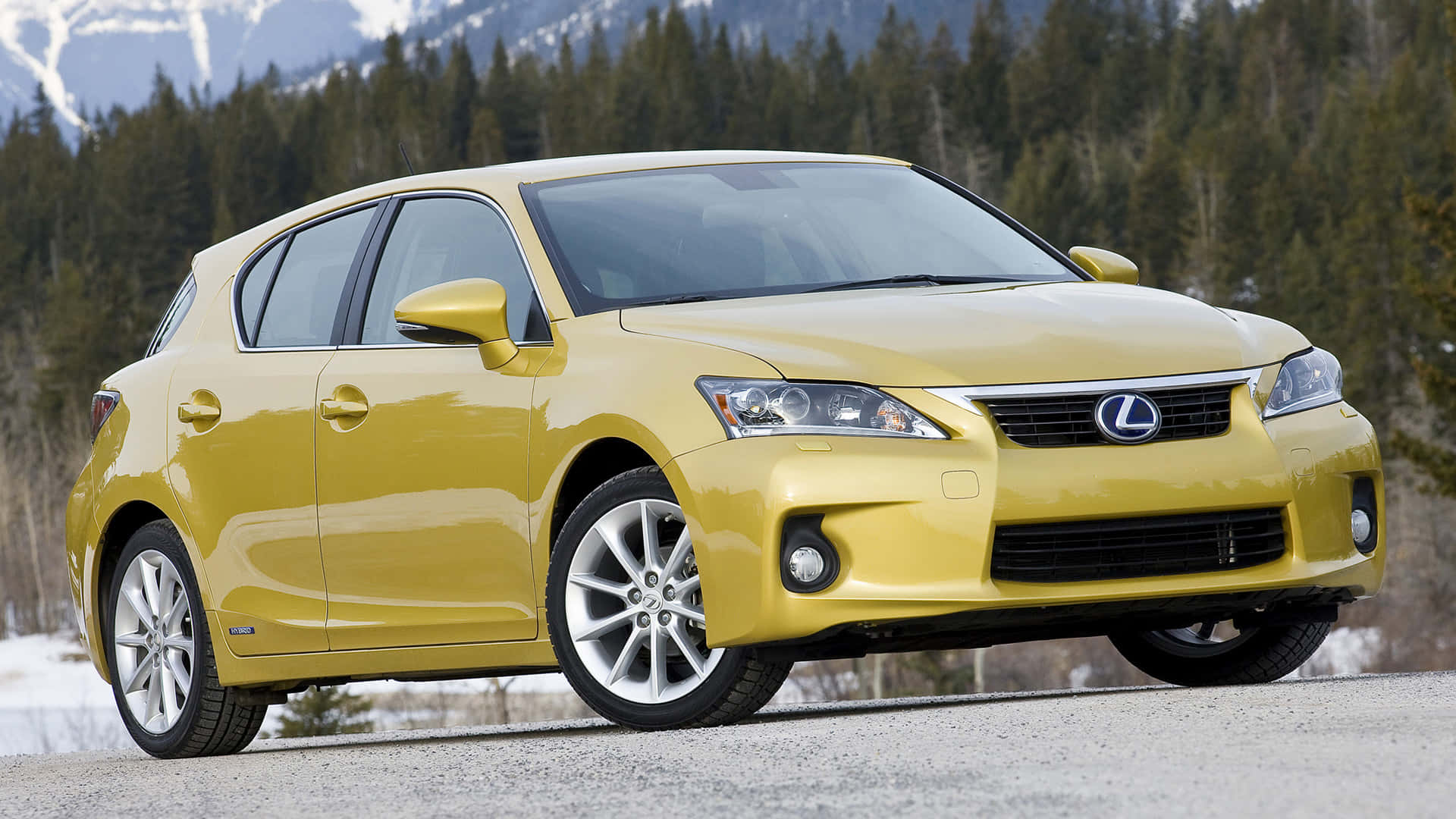 Lexus Ct 200h 桌布 壁紙 — 一輛鮮黃色的Lexus CT 200h混合動力掀背車停在碎石路上，背景是積雪的山脈和常青樹。