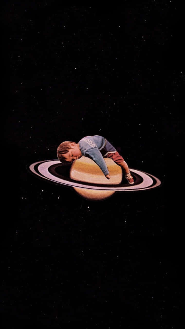  壁紙 — 一個小孩在土星環上蜷縮著安詳入睡，背景是繁星點點的宇宙。