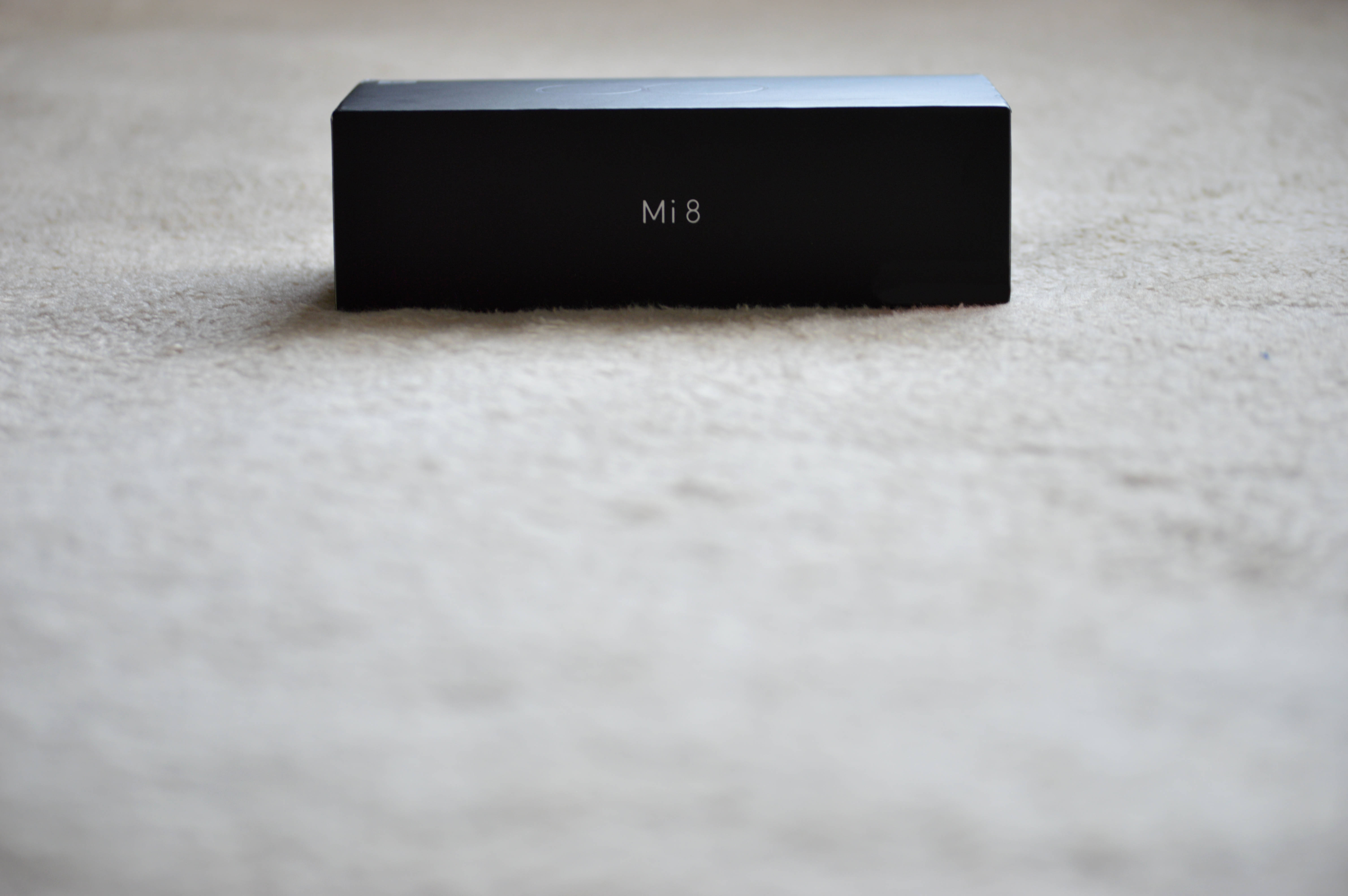 黑色 Xiaomi 喇叭 壁紙 — 一個時尚的黑色Xiaomi Mi 8盒子居中放置在柔軟的米色地毯上，景深較淺。