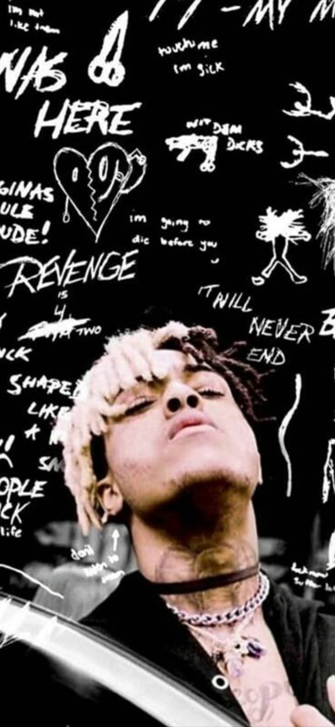 向XXXTentacion致敬 壁紙 — 一個特寫鏡頭，一名頭髮漂白、頸部有紋身的男子，在一個佈滿混亂白色塗鴉文字和圖畫的黑色背景上向上望。