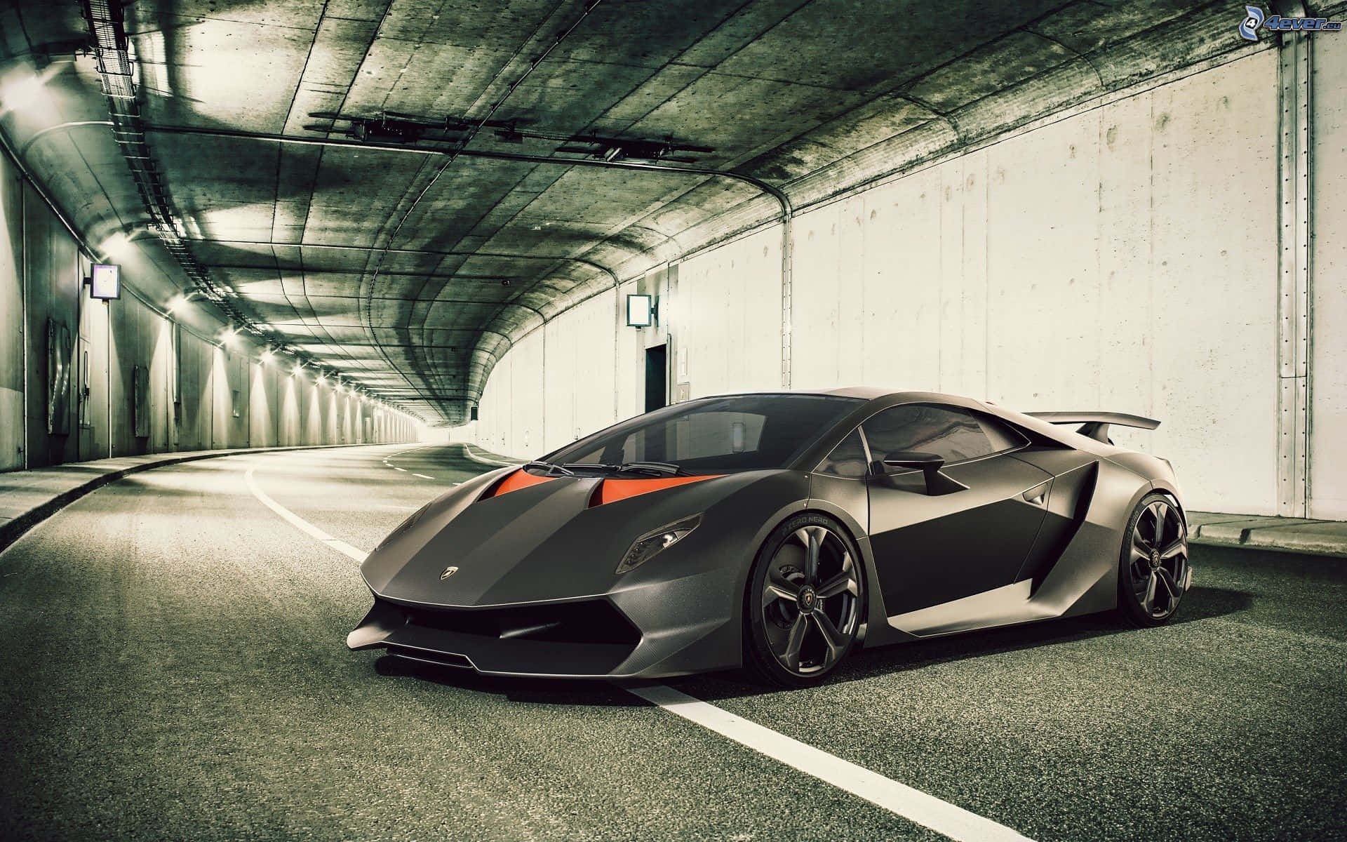 Lamborghini Sesto Elemento 桌布 壁紙 — 一輛時尚的啞光黑色林寶堅尼跑車帶有橙色點綴，停放在一條長長的混凝土隧道中。
