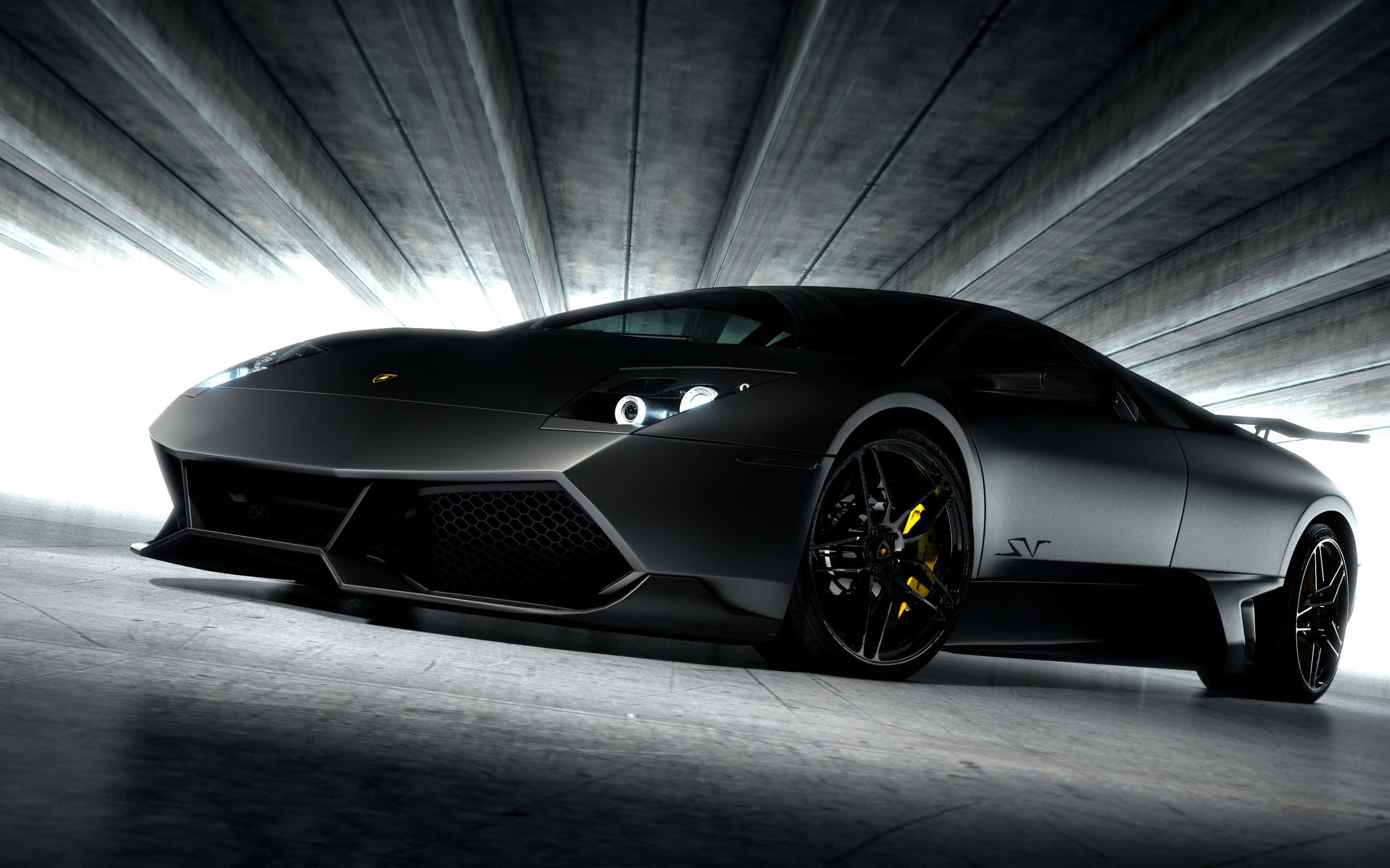 Lamborghini Murciélago 桌布 壁紙 — 一輛光滑的啞光黑色林寶堅尼Reventon跑車，配備黃色制動卡鉗，在混凝土隧道中被戲劇性地照亮。
