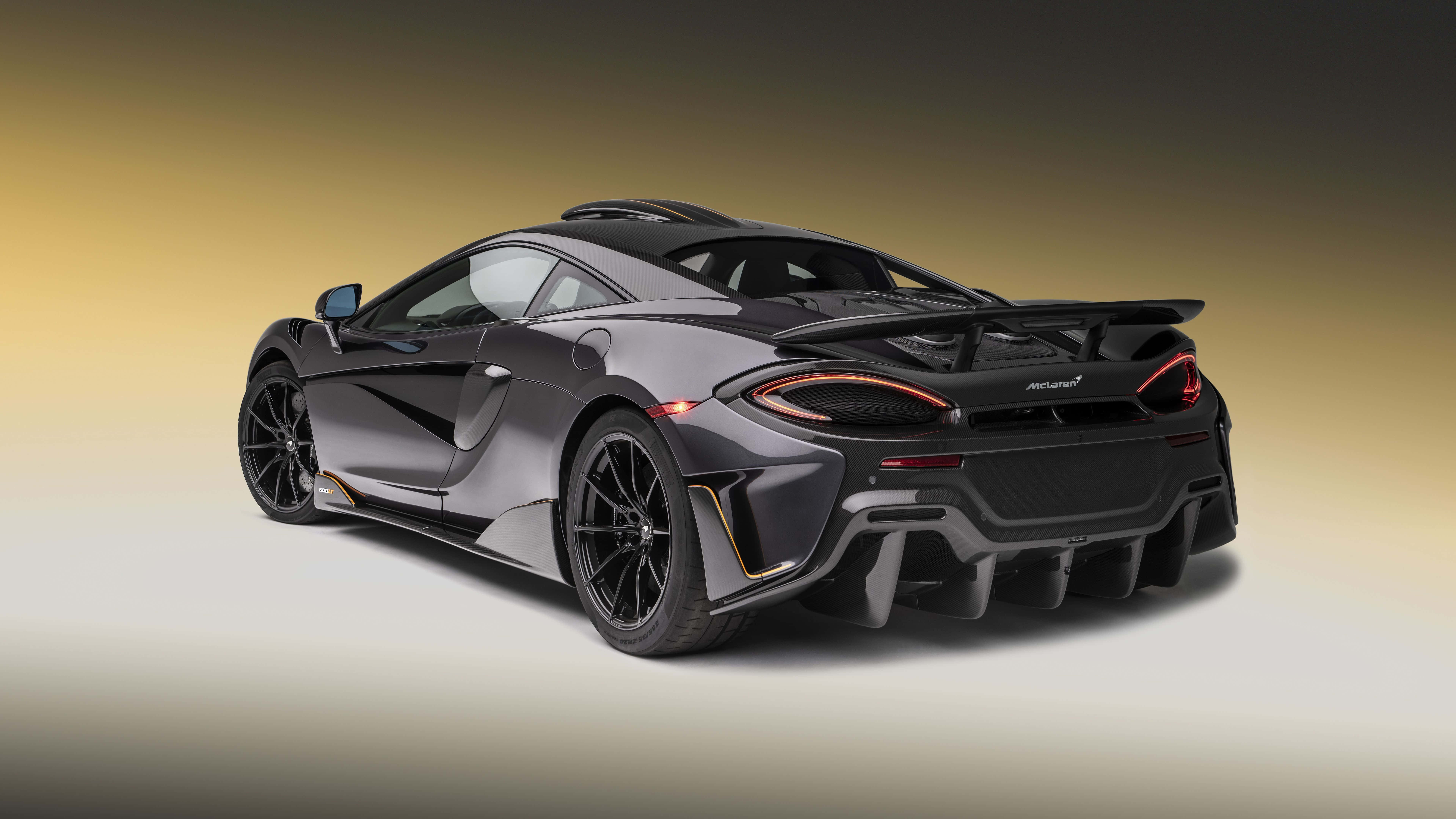 Mclaren 600lt 桌布 壁紙 — 一輛時尚的啞光灰色McLaren跑車，帶有發光的橙色尾燈，在黃色和灰色的漸變工作室背景中展示。