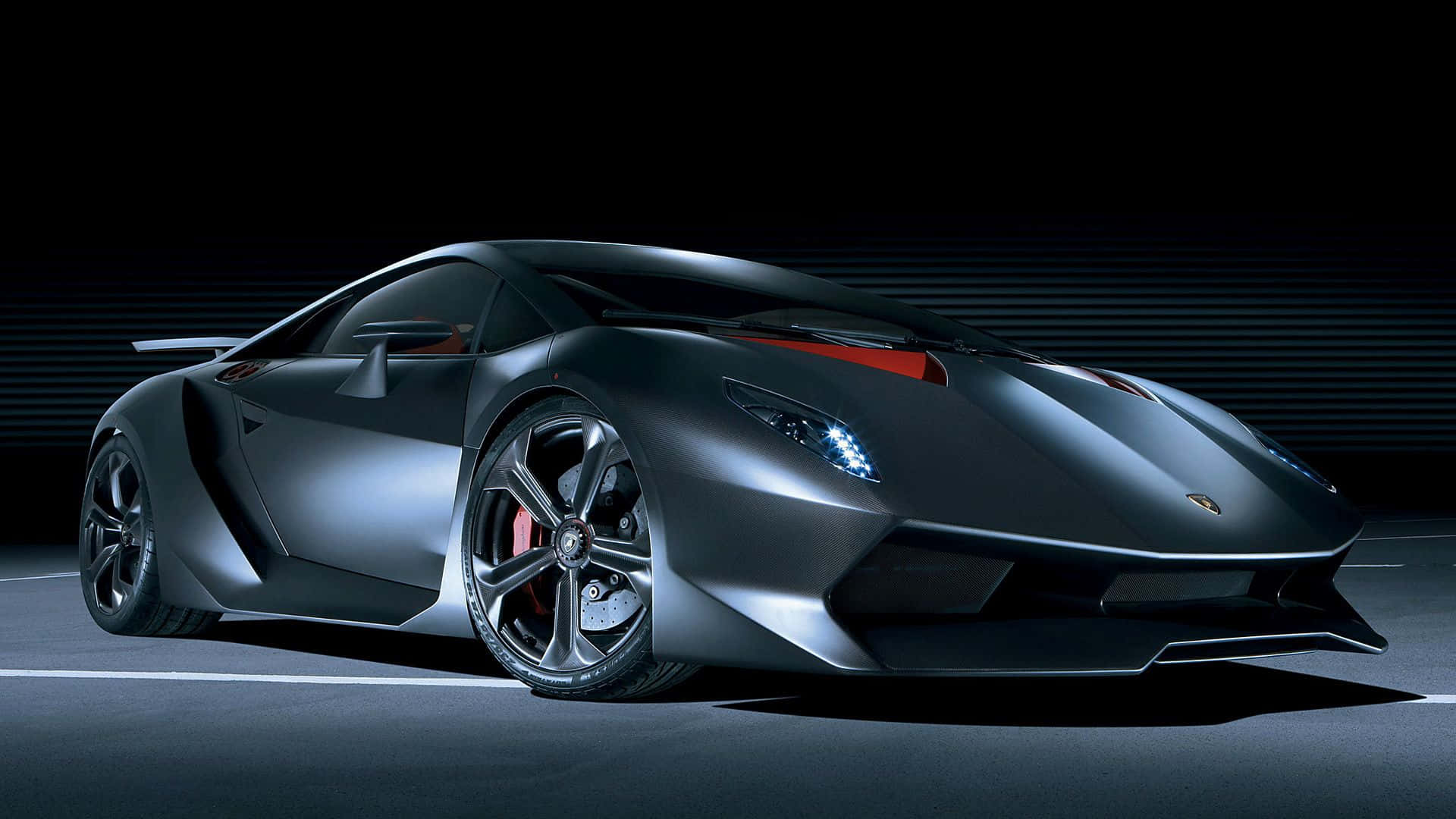 Lamborghini Sesto Elemento 桌布 壁紙 — 一輛時尚的啞光黑色林寶堅尼跑車，帶有紅色點綴，在黑暗道路上的工作室燈光下閃耀。