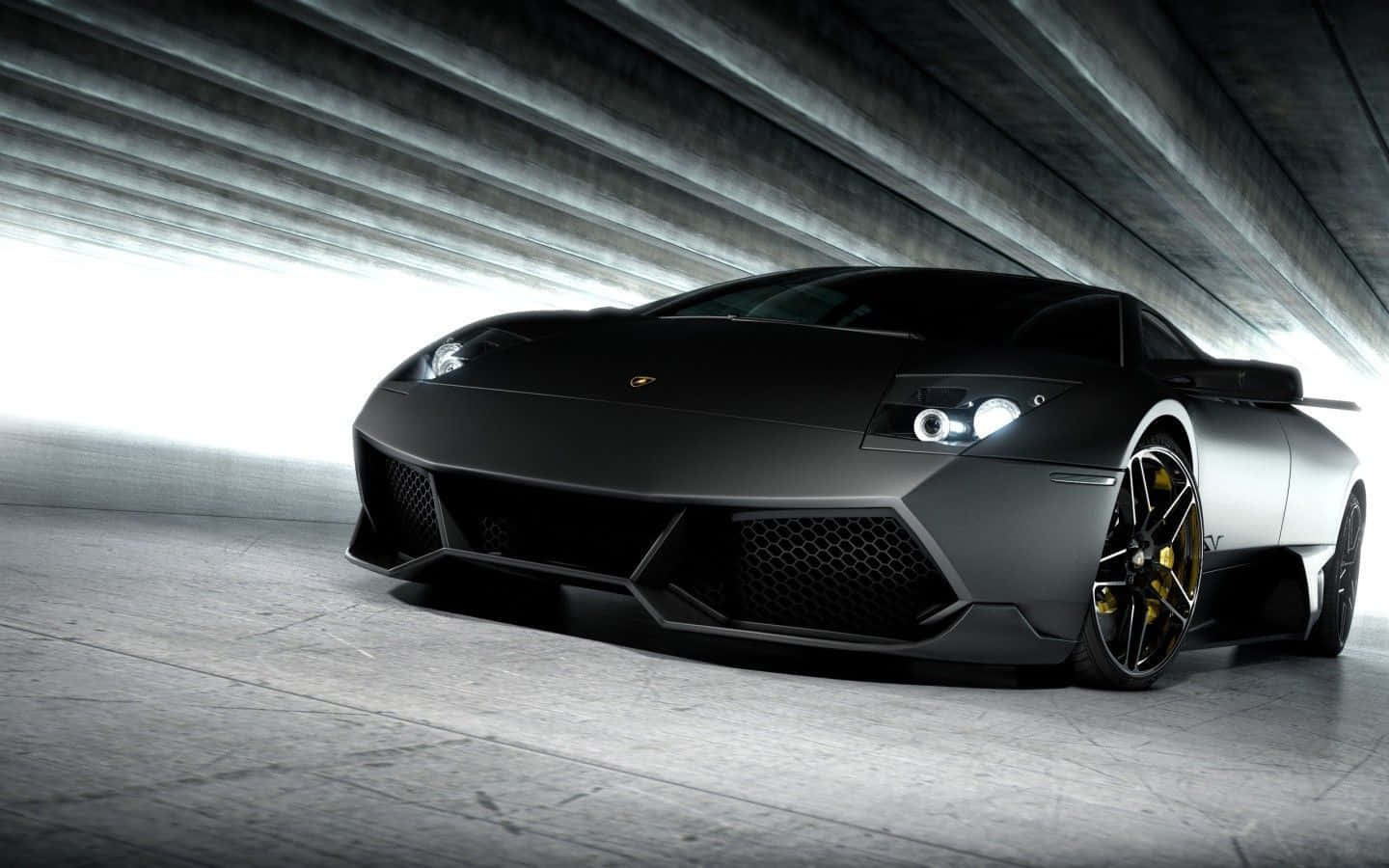 Lamborghini Murciélago 桌布 壁紙 — 一輛啞光黑色林寶堅尼跑車配金色輪圈，在混凝土隧道天花下被戲劇性地照亮。