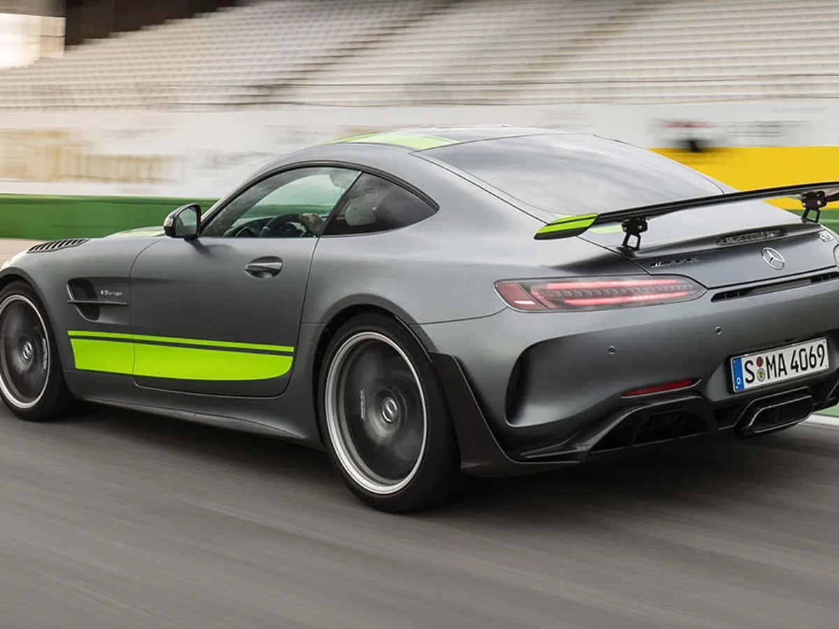  壁紙 — 一架啞光灰色的 Mercedes-AMG GT R 帶有螢光綠色點綴，在賽道上疾馳，背景是模糊的看台。