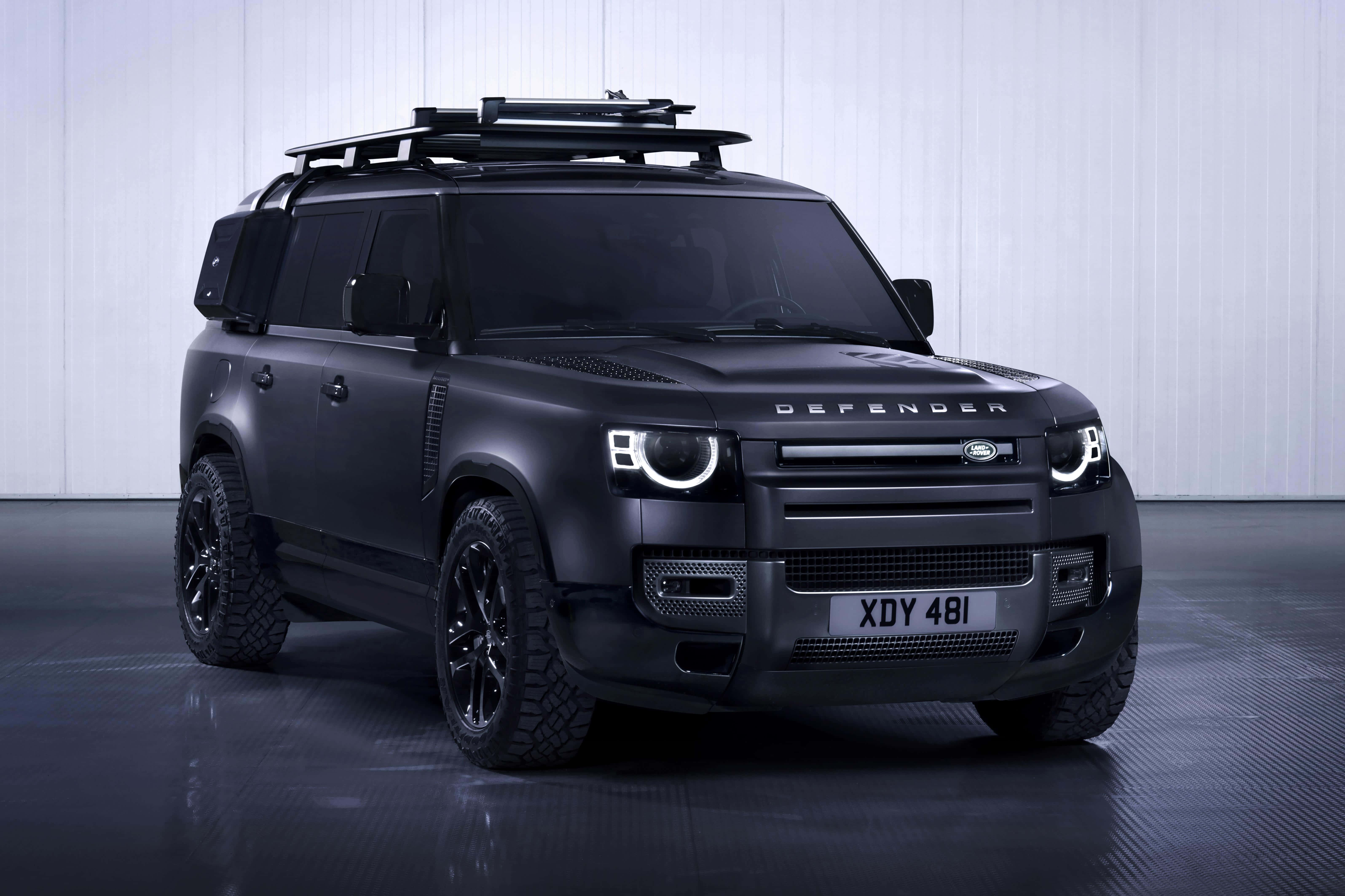 Land Rover Defender 桌布 壁紙 — 一輛啞光黑色的Land Rover Defender配備車頂架，位於極簡風格的工作室中，地板具有反射效果，牆面為垂直鑲板。