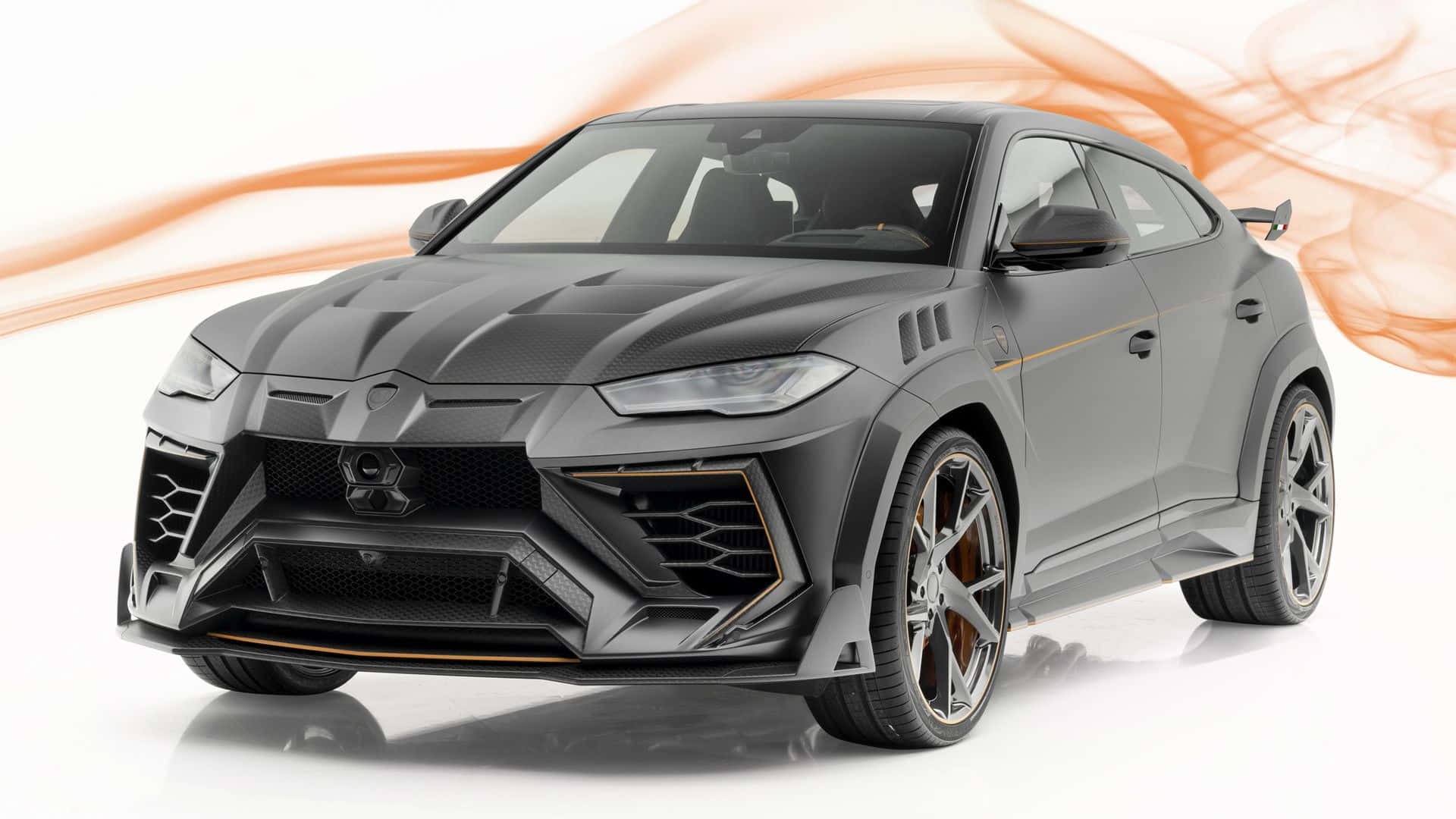 Lamborghini Urus 桌布 壁紙 — 啞光灰色林寶堅尼 Urus，帶橙色點綴和動態煙霧漩渦，在白色工作室背景前。