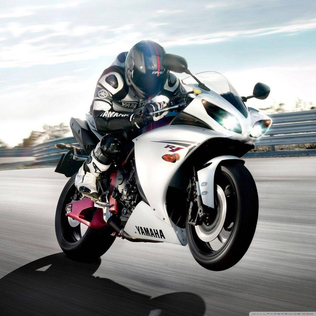 Yamaha 4K摩托車 壁紙 — 一名騎手在明亮的天空下，在賽道上騎著白色Yamaha R1電單車傾斜入彎。