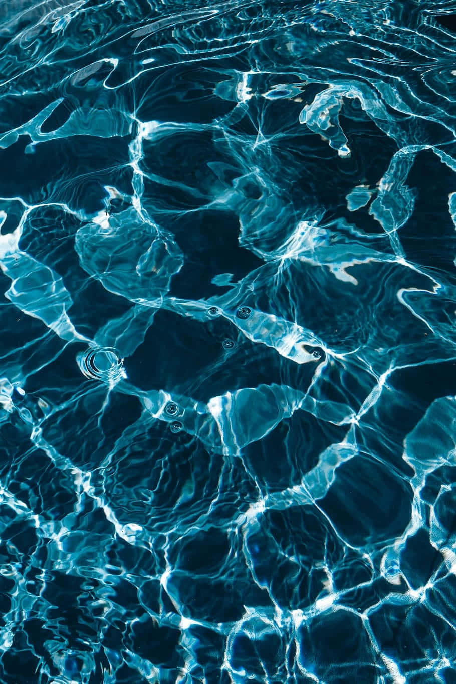 Abstract Water 桌布 壁紙 — 陽光在深藍色水面上折射，形成閃爍的光影圖案和輕柔的漣漪。