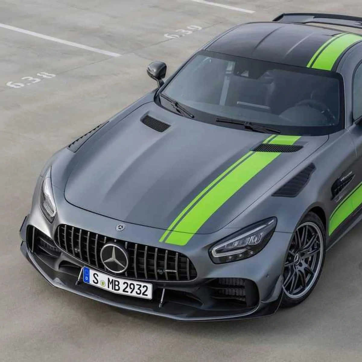  壁紙 — 一架啞光灰色 Mercedes-AMG GT 帶有螢光綠色賽車條紋，停放在混凝土場地上。