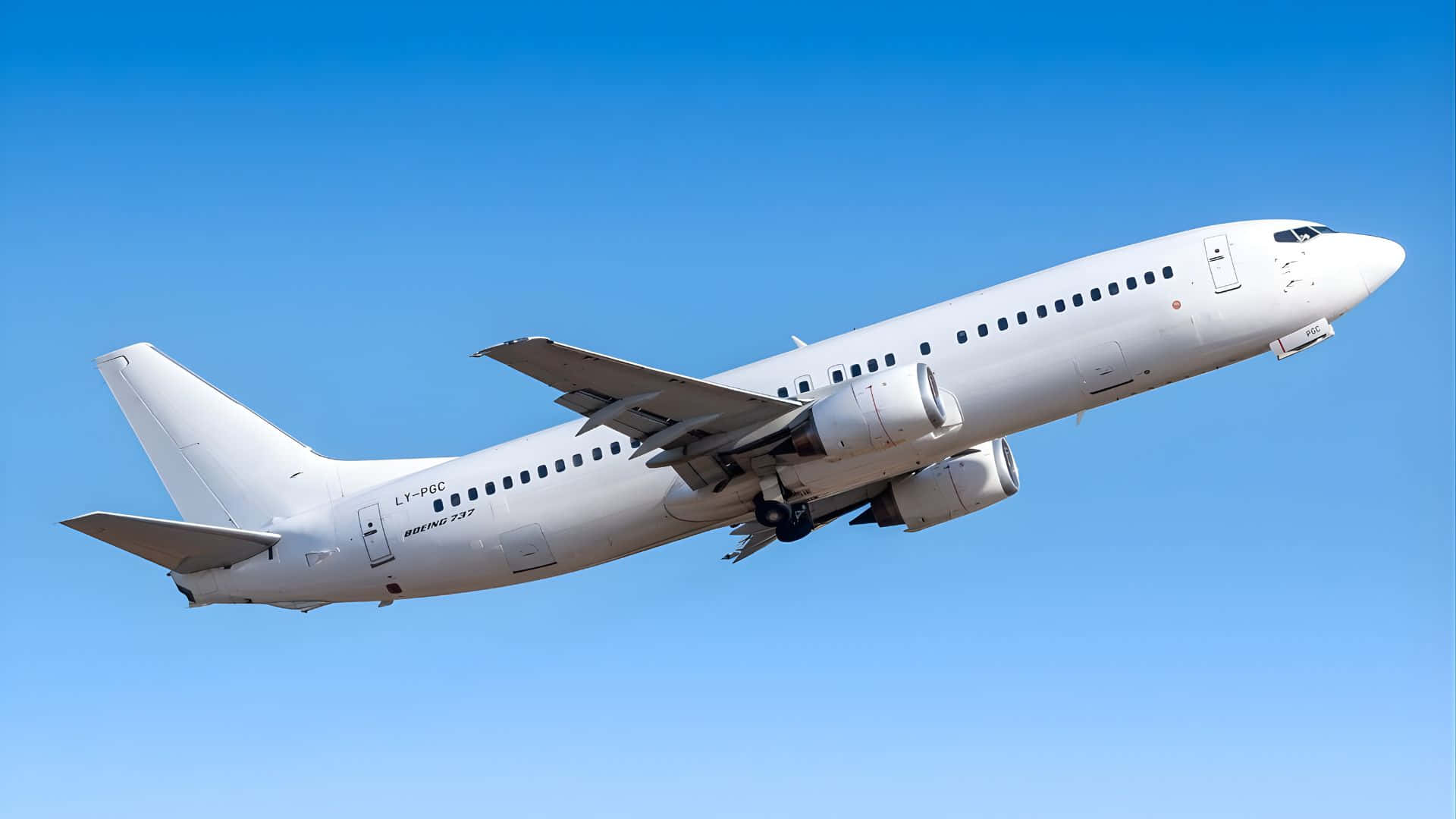  壁紙 — 一架白色波音737飛機在晴朗的藍天中翱翔，起落架已放下。