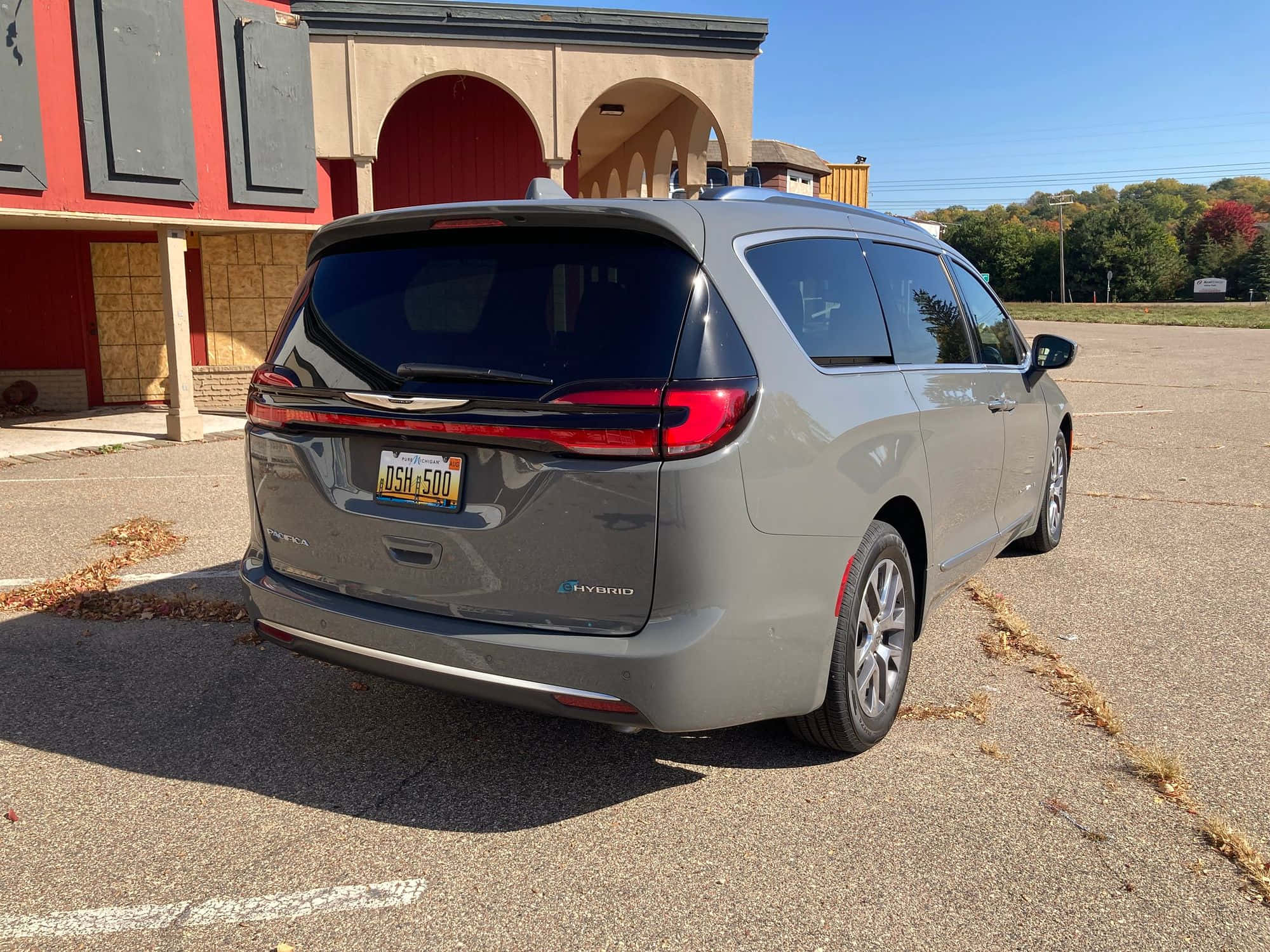Chrysler Pacifica 桌布 壁紙 — 一架灰色克萊斯勒Pacifica Hybrid迷你貨車停泊在停車場，有秋葉，在明亮的日光下。