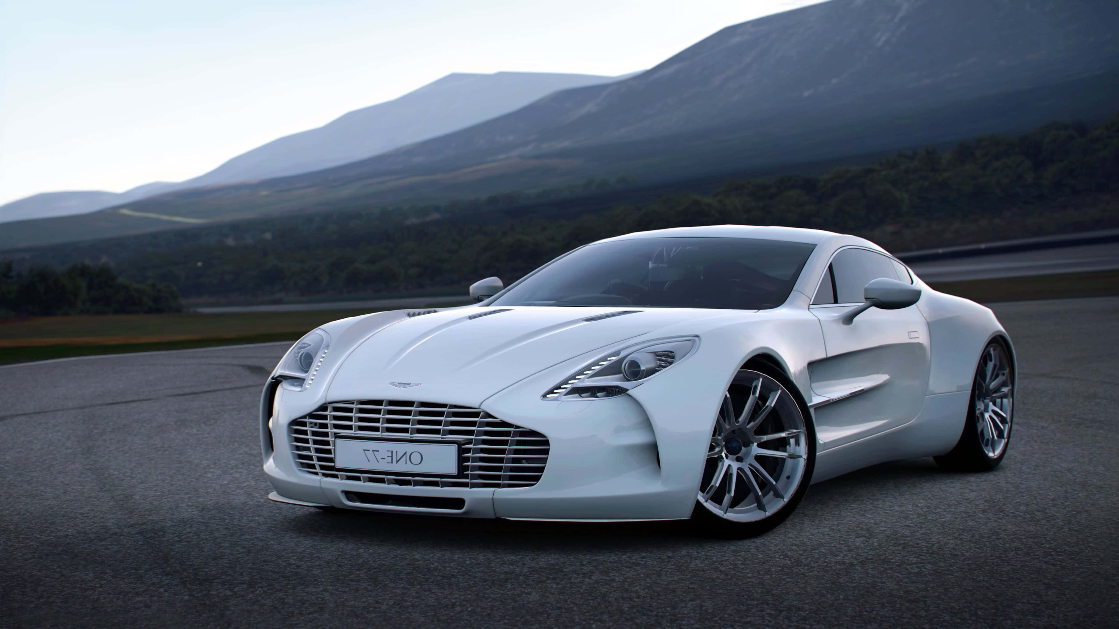 Aston Martin One-77 桌布 壁紙 — 一架流線型白色Aston Martin One-77跑車在柔和日光下沿著蜿蜒的山路滑行。