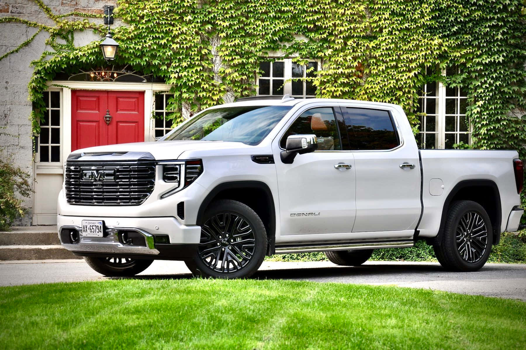 Gmc Sierra 桌布 壁紙 — 一架時尚的白色GMC Sierra Denali pickup truck停泊在一間有紅色門、被藤蔓覆蓋的石屋前的車道上。