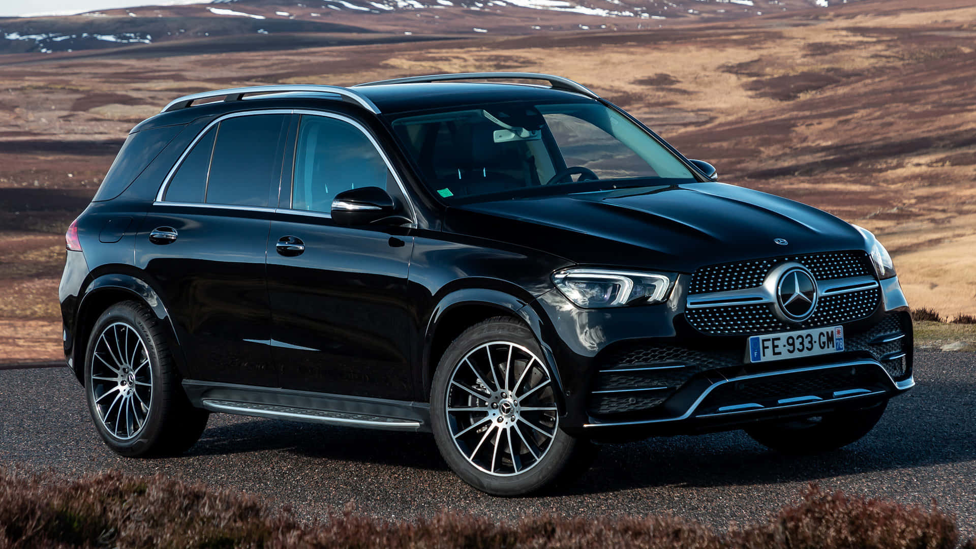 Mercedes Benz Gle-class 桌布 壁紙 — 一架時尚的黑色 Mercedes-Benz GLE SUV 停泊在碎石路上，背景是崎嶇的棕色和積雪的山脈。