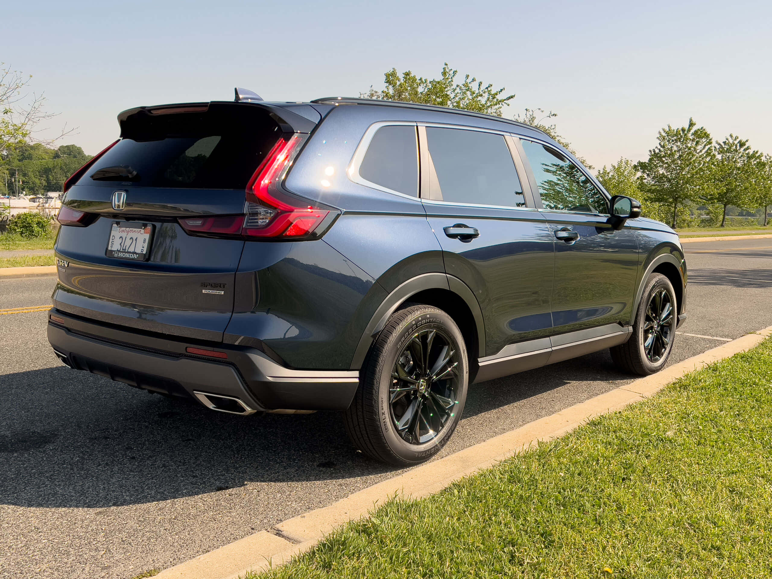 Honda Cr-v 桌布 壁紙 — 一架時尚的深灰色本田 CR-V Sport 在陽光明媚的日子裡停在草地路邊，背景有樹木。