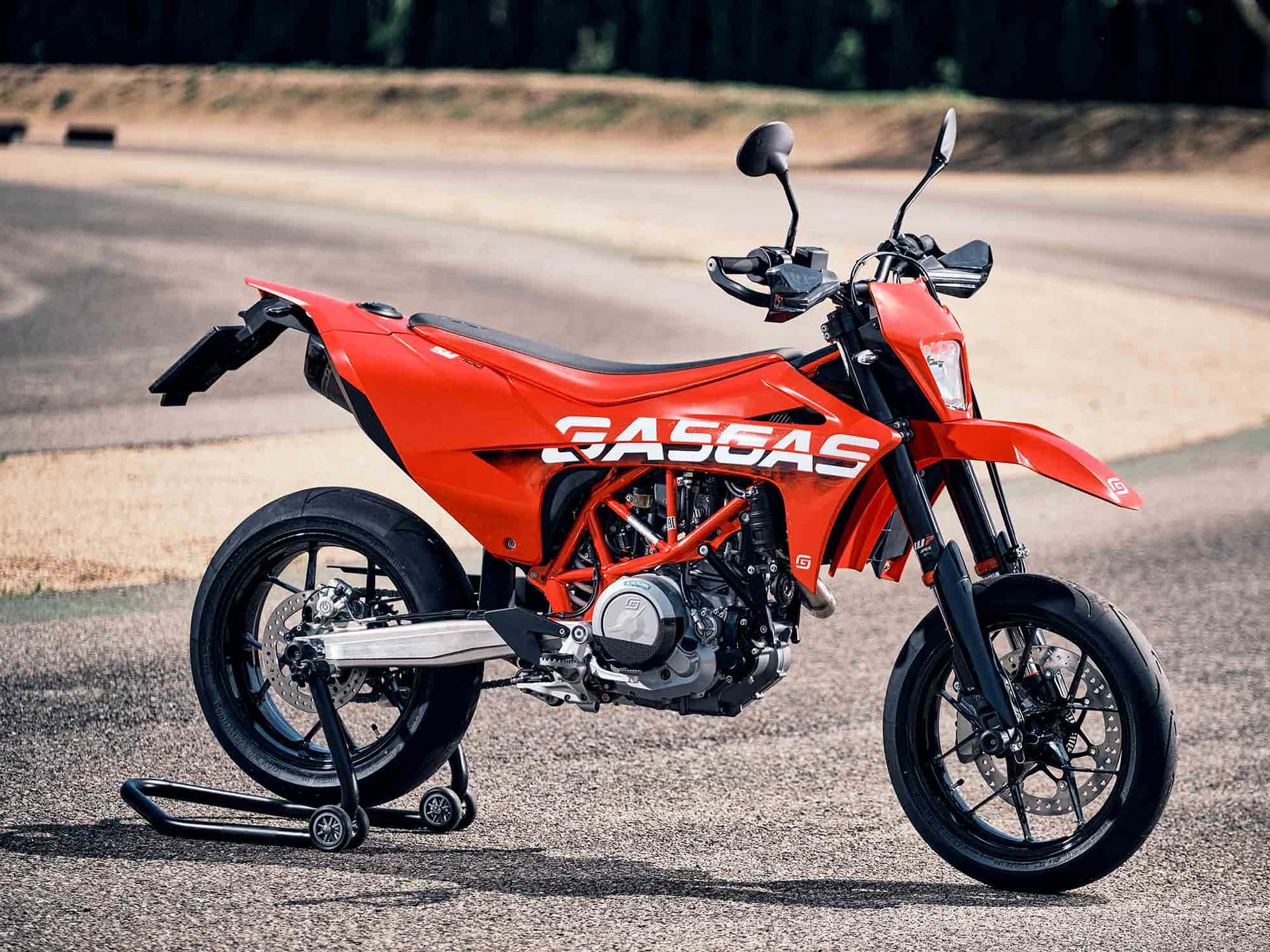  壁紙 — 一架鮮橙色的KTM 350 EXC-F越野電單車停在碎石路上，背景是樹木茂密的山丘。