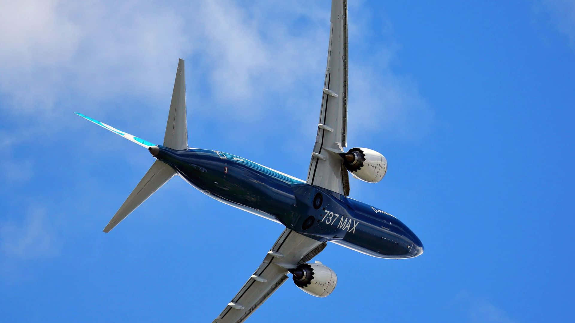  壁紙 — 一架波音737 MAX飛機在清澈藍天和縷縷白雲中翱翔。