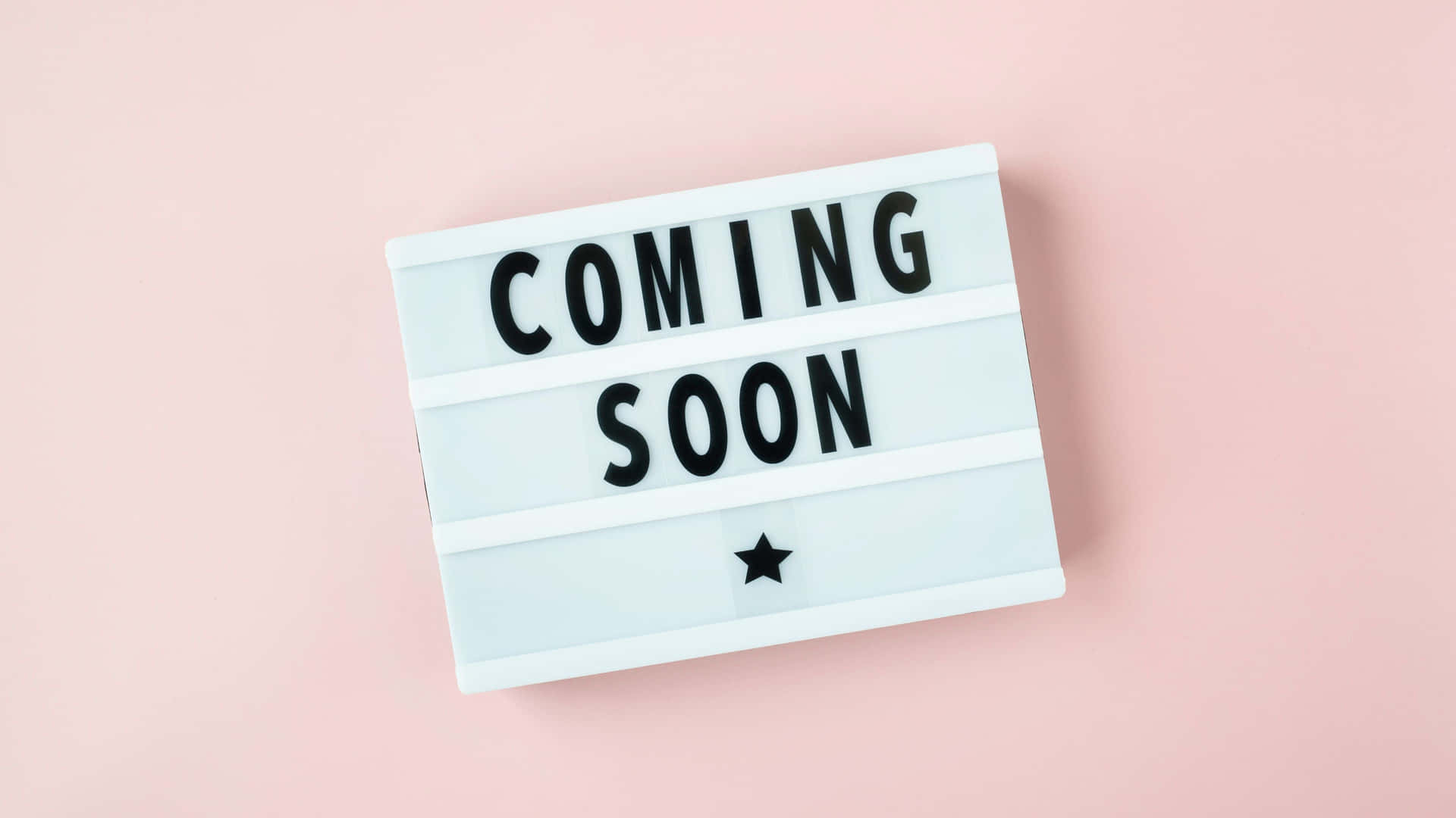 一個白色燈箱，上面有黑色字母寫著「COMING SOON」，還有一顆星星在粉紅色背景上。