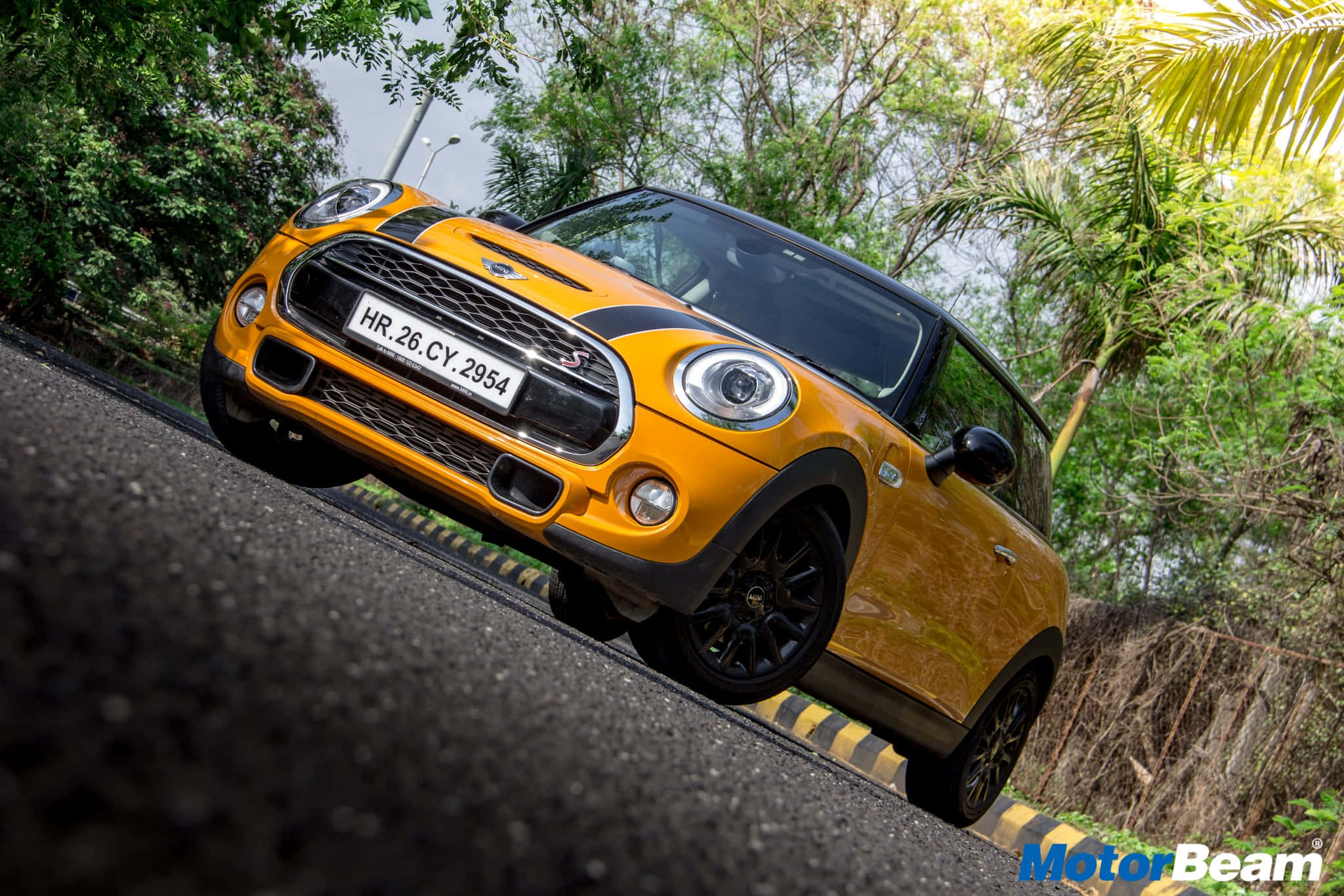 Mini Cooper S 桌布 壁紙 — 一輛充滿活力的橙色MINI Cooper S在蜿蜒的道路上行駛，周圍環繞著茂密的綠色熱帶植物。