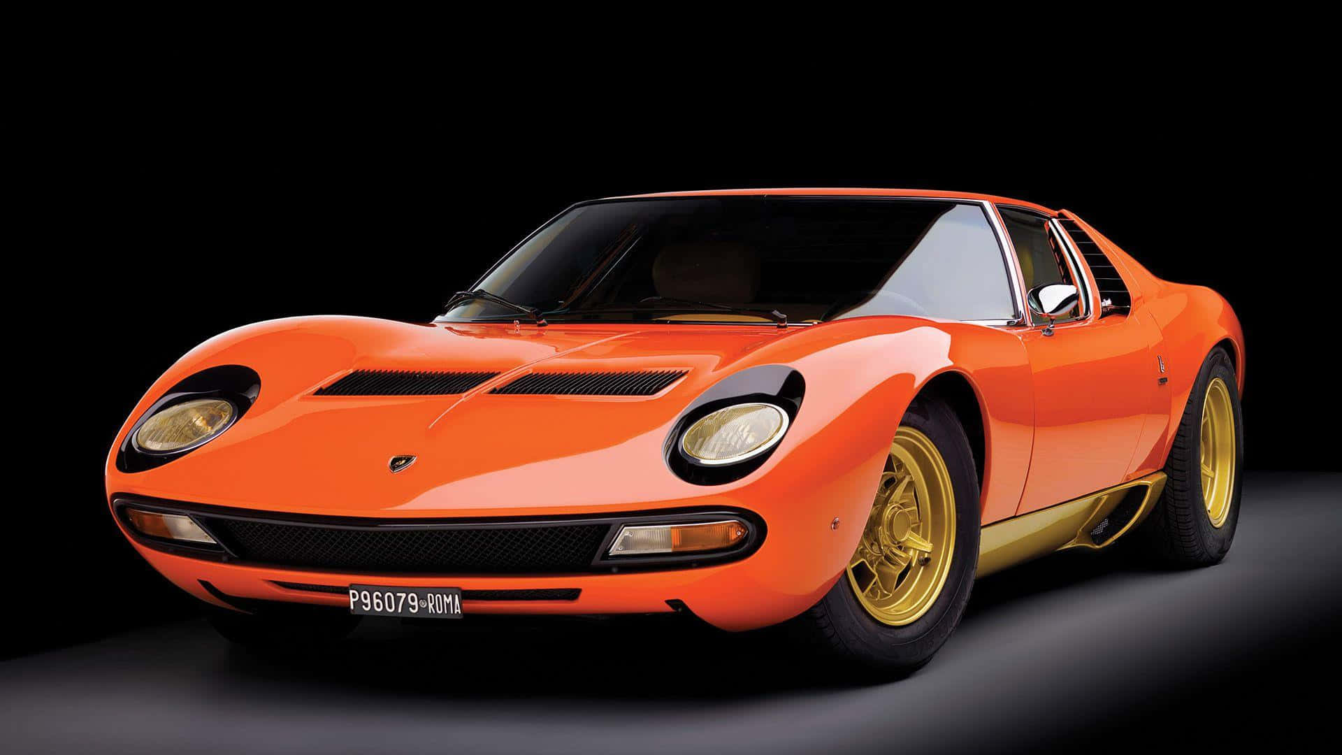 Lamborghini Miura 桌布 壁紙 — 一輛充滿活力的橙色林寶堅尼Miura跑車，配備金色輪圈，在純黑色工作室背景前蓄勢待發。