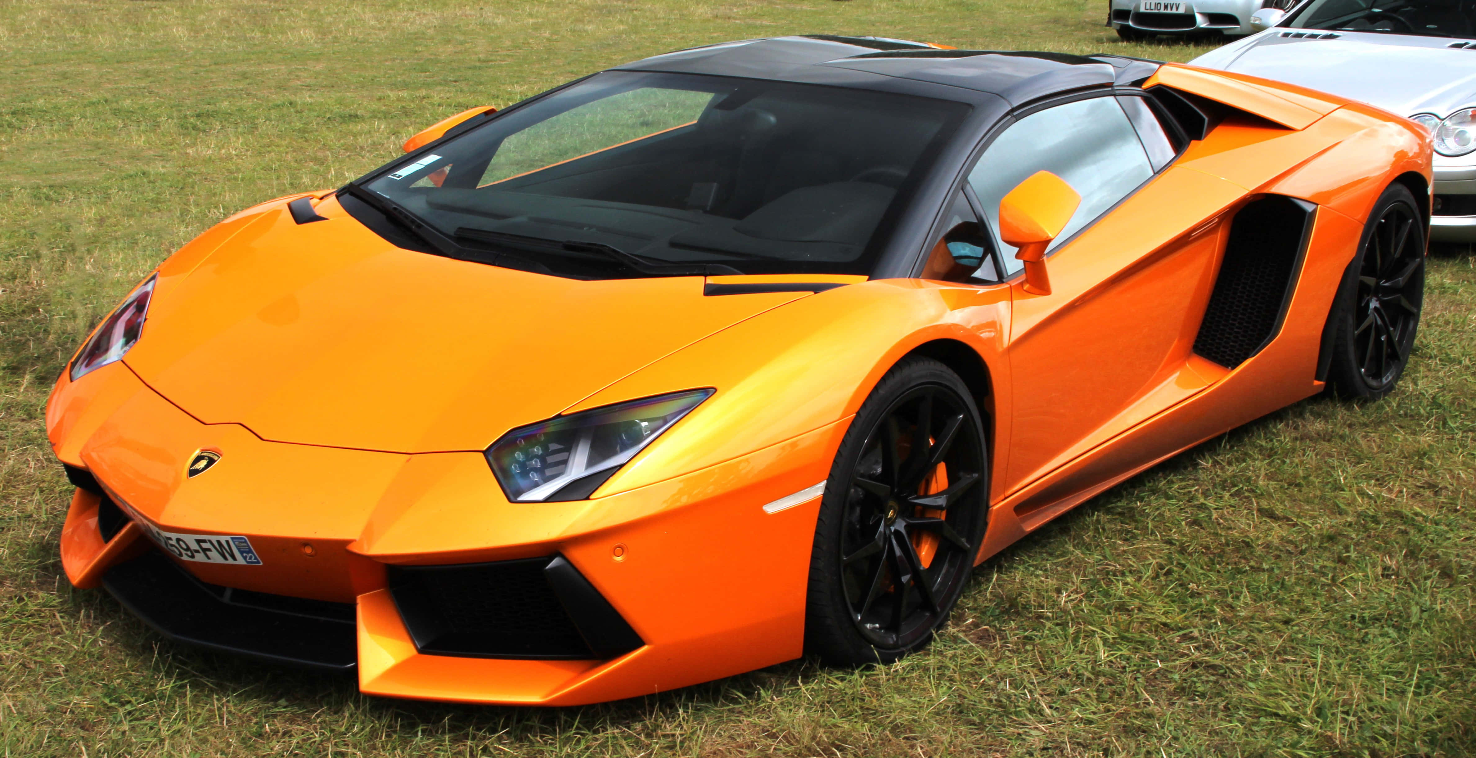 Lamborghini Reventón 桌布 壁紙 — 一輛充滿活力的橙色林寶堅尼Aventador跑車停在草地上，帶有黑色飾邊和流線型空氣動力學設計。