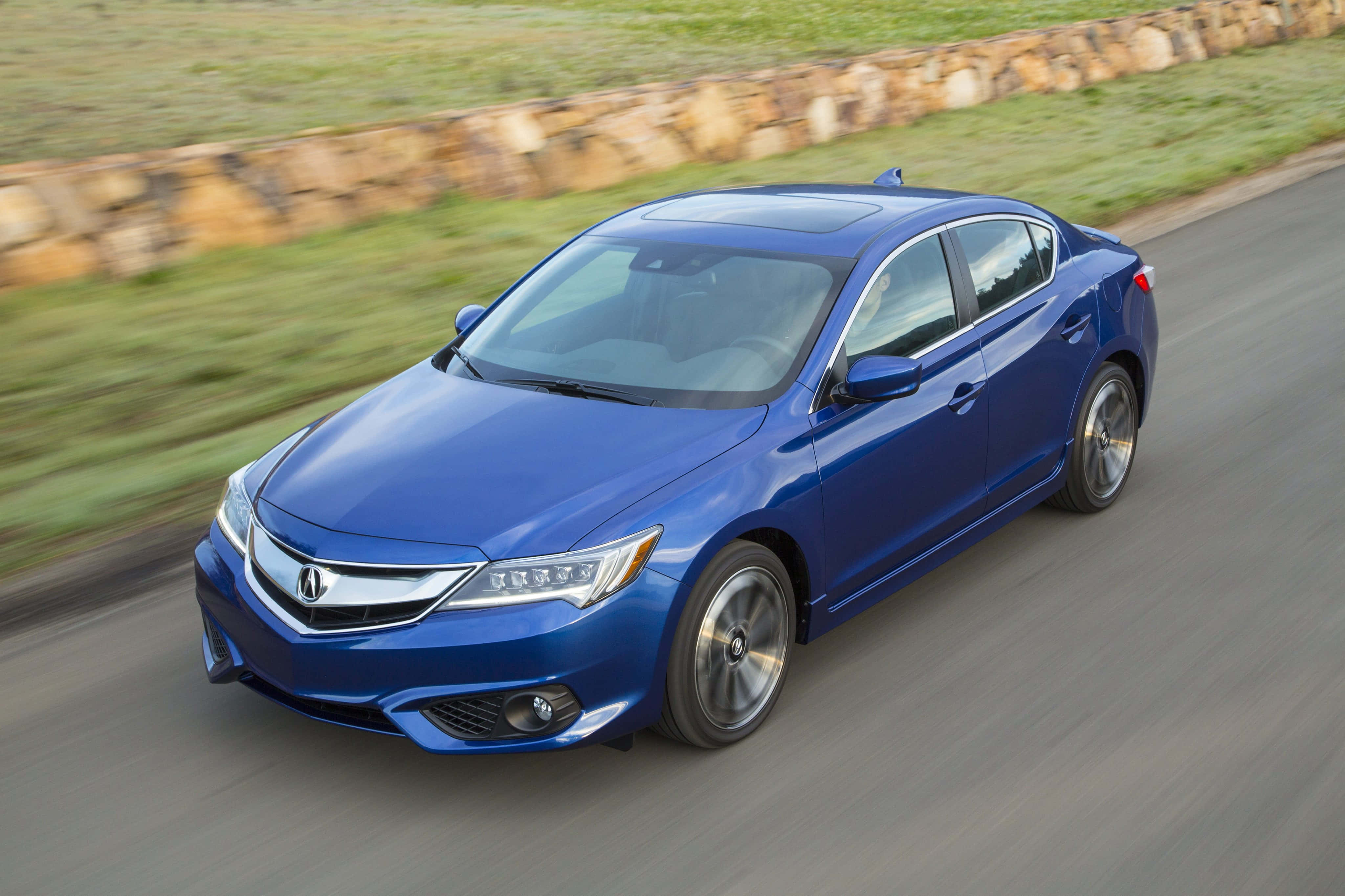 Acura Ilx 桌布 壁紙 — 一輛充滿活力的藍色轎車沿著蜿蜒的道路疾馳，背景是模糊的綠色草地和石牆。
