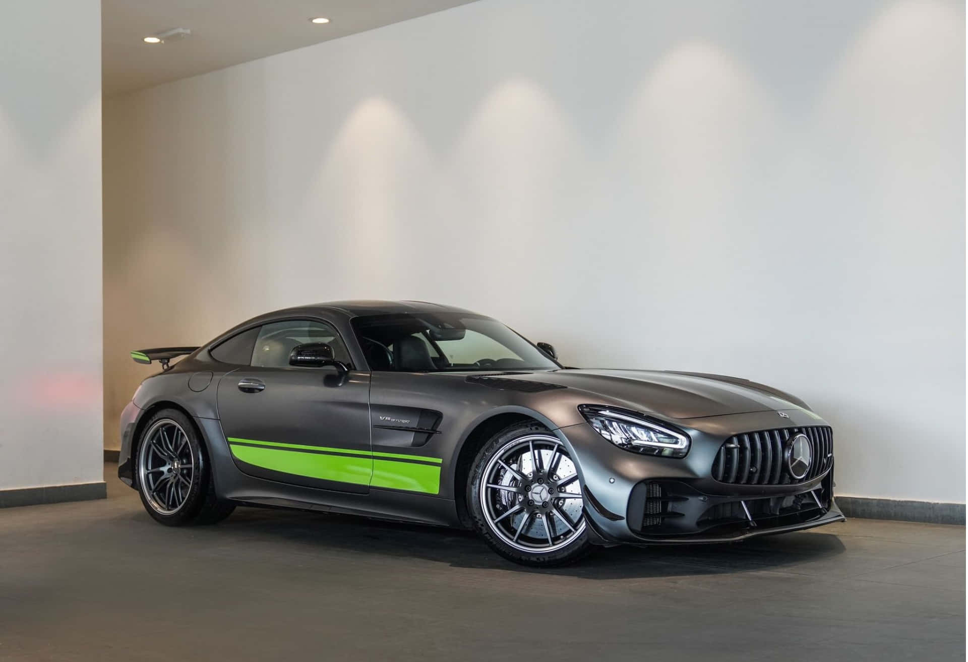  壁紙 — 一輛帶有鮮綠色條紋的啞光灰色Mercedes-AMG GT Black Series在極簡白色畫廊空間的聚光燈下閃閃發光。