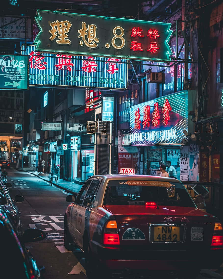  壁紙 — 一輛紅色出租車停在繁華亞洲城市小巷中閃爍的霓虹燈招牌下。