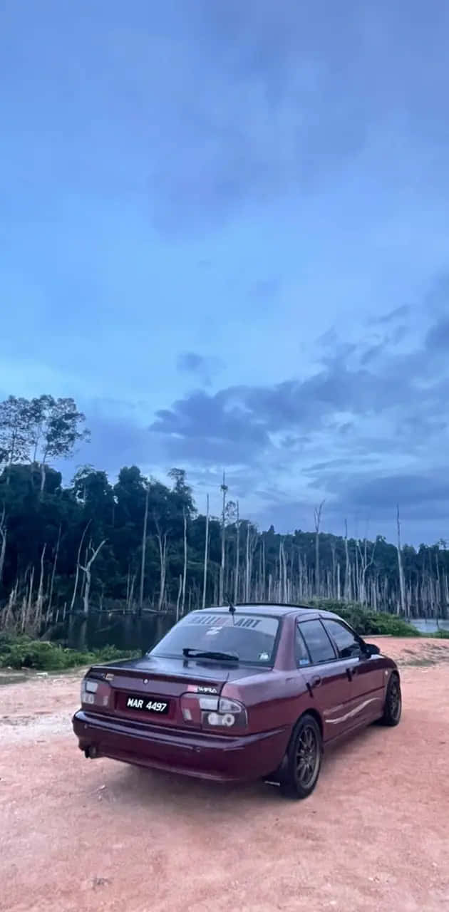  壁紙 — 一輛栗色轎車停泊在微紅泥土上，背景是陰鬱的暮色天空和森林。