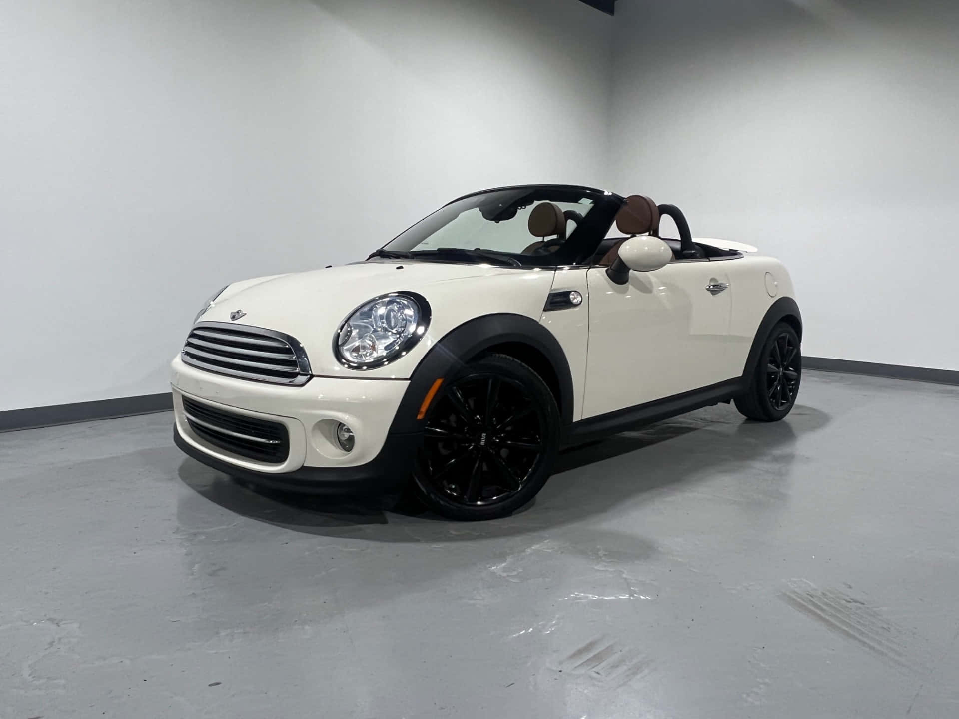  壁紙 — 一輛純白色的MINI Cooper開篷車，帶有黑色飾件和車輪，停放在簡約的攝影棚空間中。