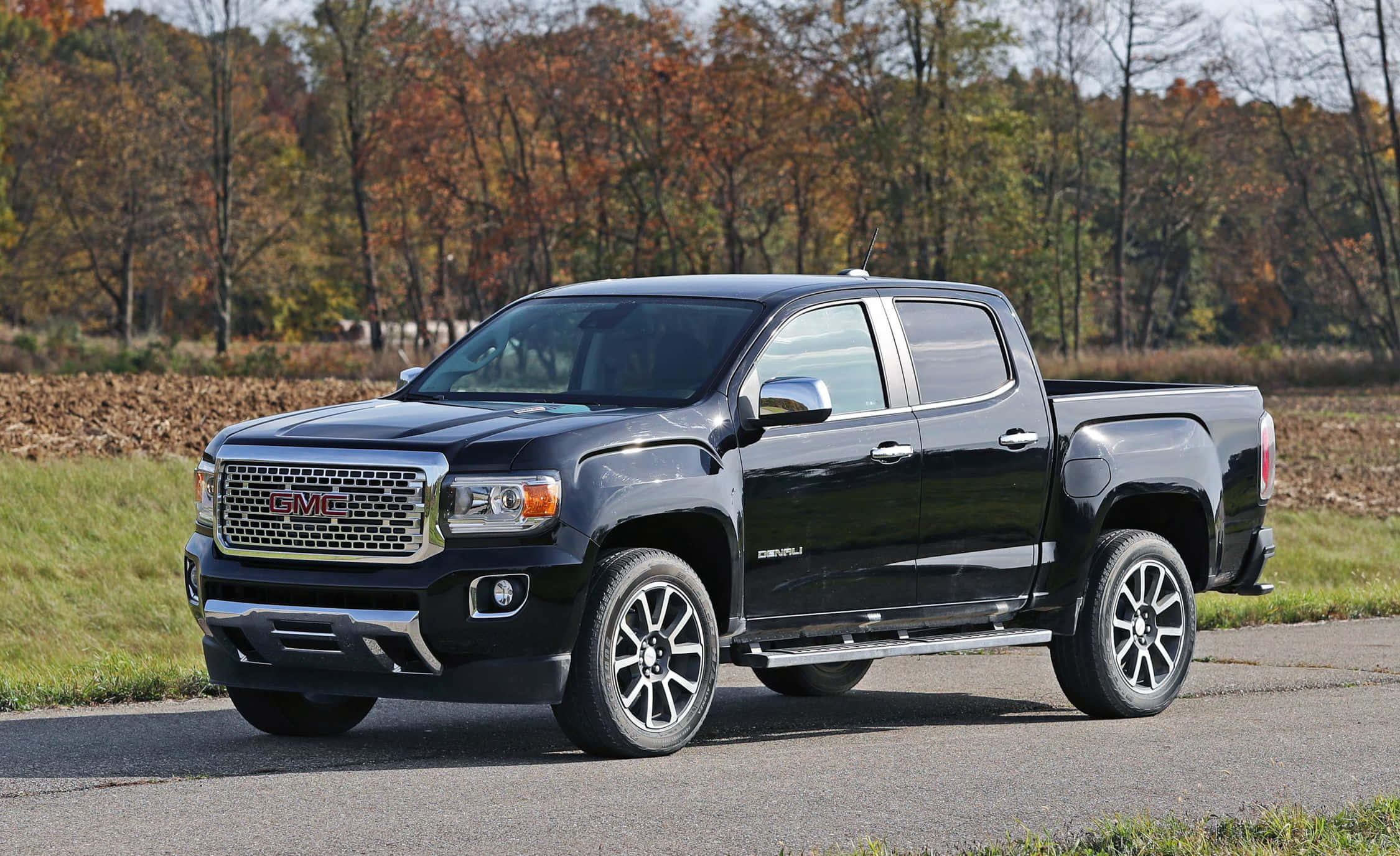 Gmc Canyon 桌布 壁紙 — 一輛時尚的黑色GMC Canyon皮卡車停在鋪砌的道路上，背景是秋天的樹木。