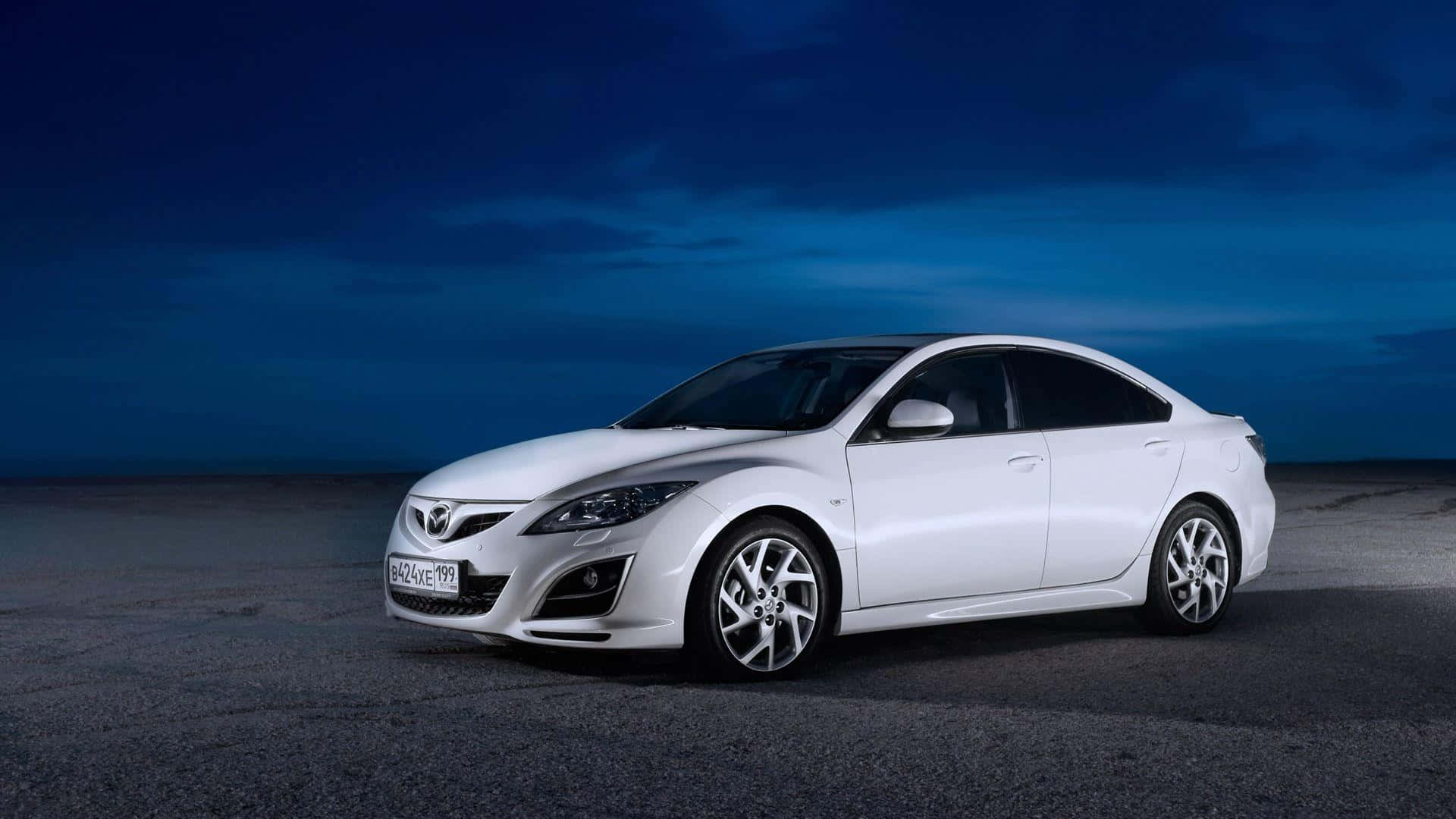 Mazda 6 桌布 壁紙 — 一輛時尚的白色萬事得轎車在暮色天空下，在廣闊的空曠瀝青路面上閃閃發光。