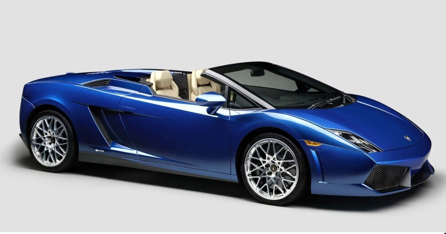 Lamborghini Gallardo 桌布 壁紙 — 一輛時尚的藍色林寶堅尼Gallardo Spyder開篷跑車，配備米色皮革座椅和銀色輪圈，背景為純灰色。