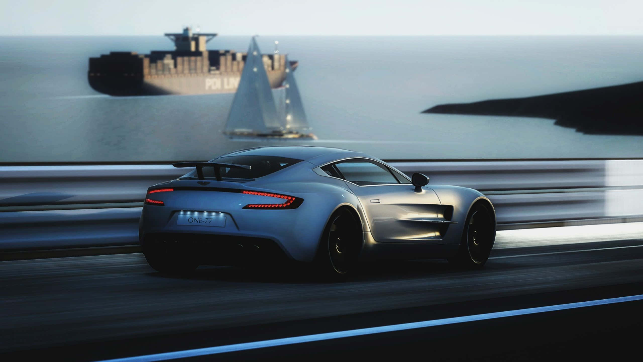 Aston Martin One-77 桌布 壁紙 — 一輛時尚的銀色跑車沿著海岸公路飛馳，遠處隱約可見一艘貨船和帆船。